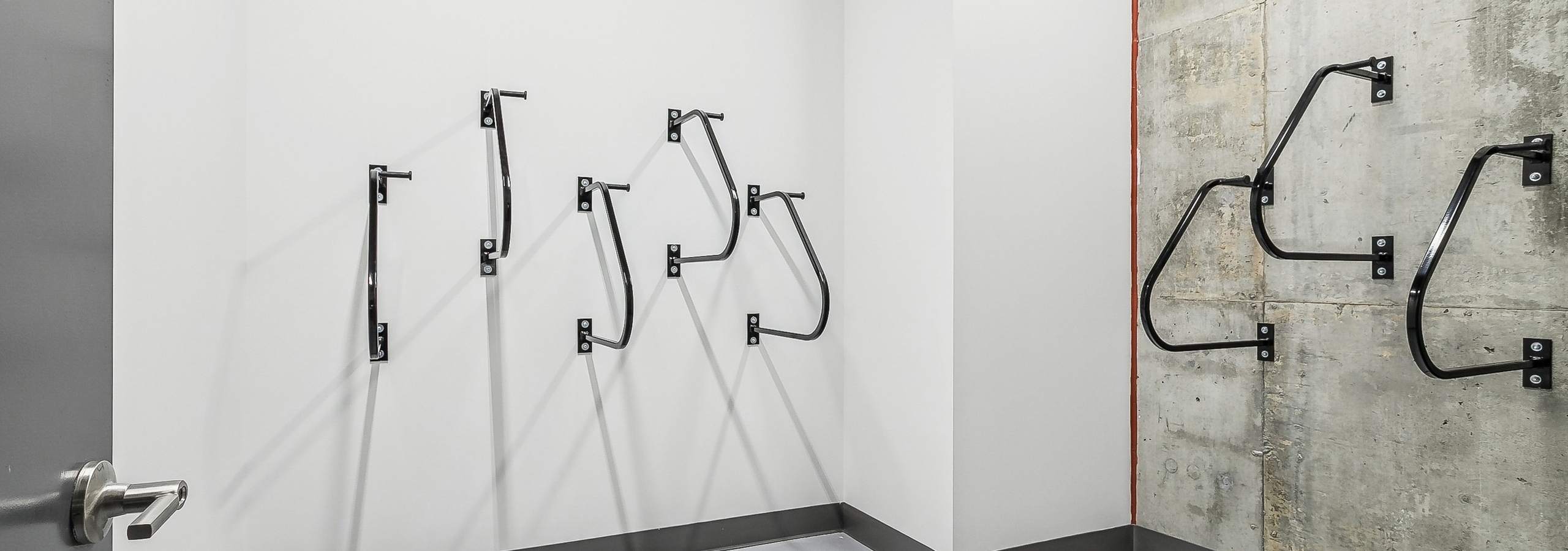 Minimalist bike storage room at AMLI Atlantic Station with several black wall mounted racks on white and gray concrete walls