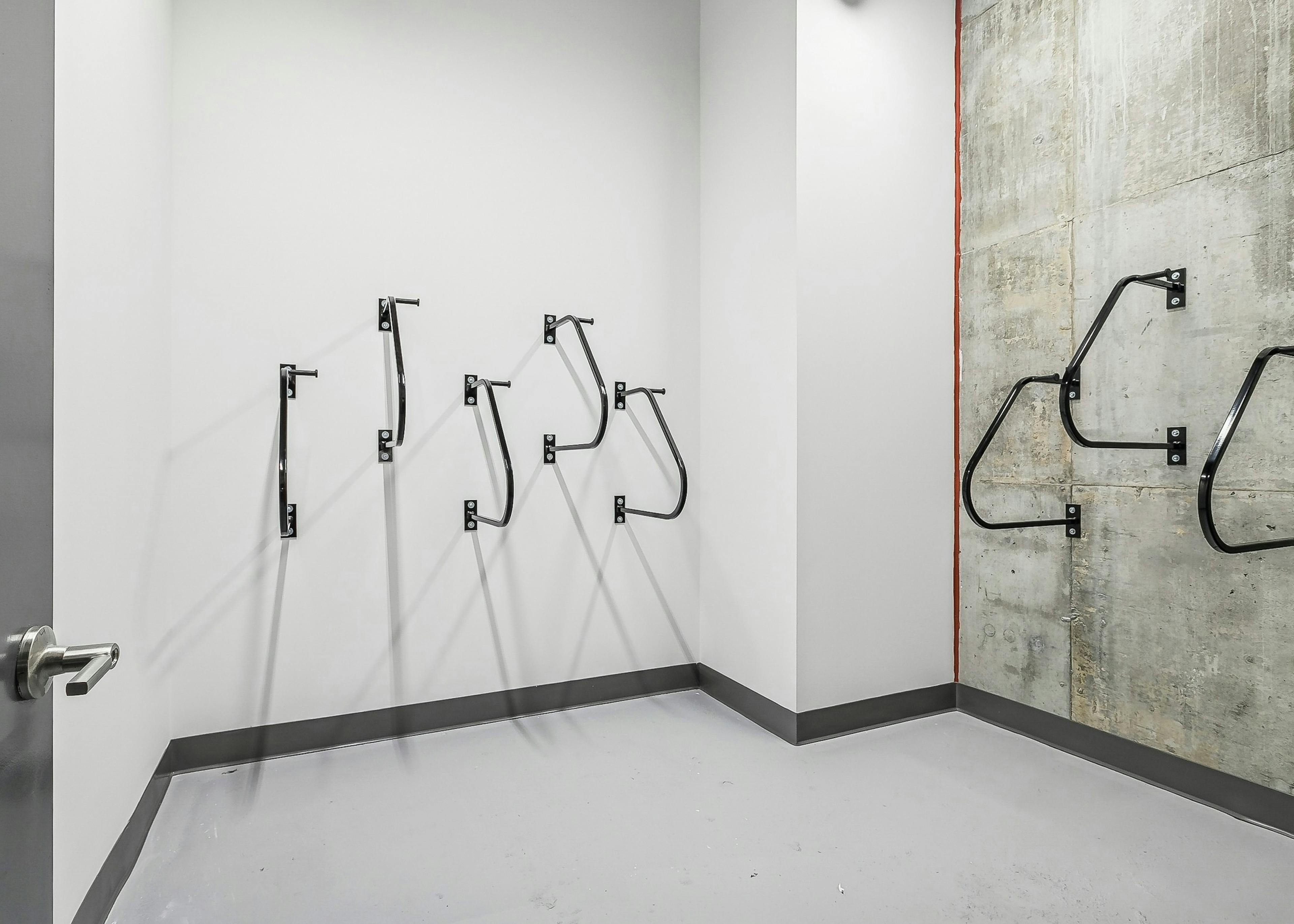 Minimalist bike storage room at AMLI Atlantic Station with several black wall mounted racks on white and gray concrete walls