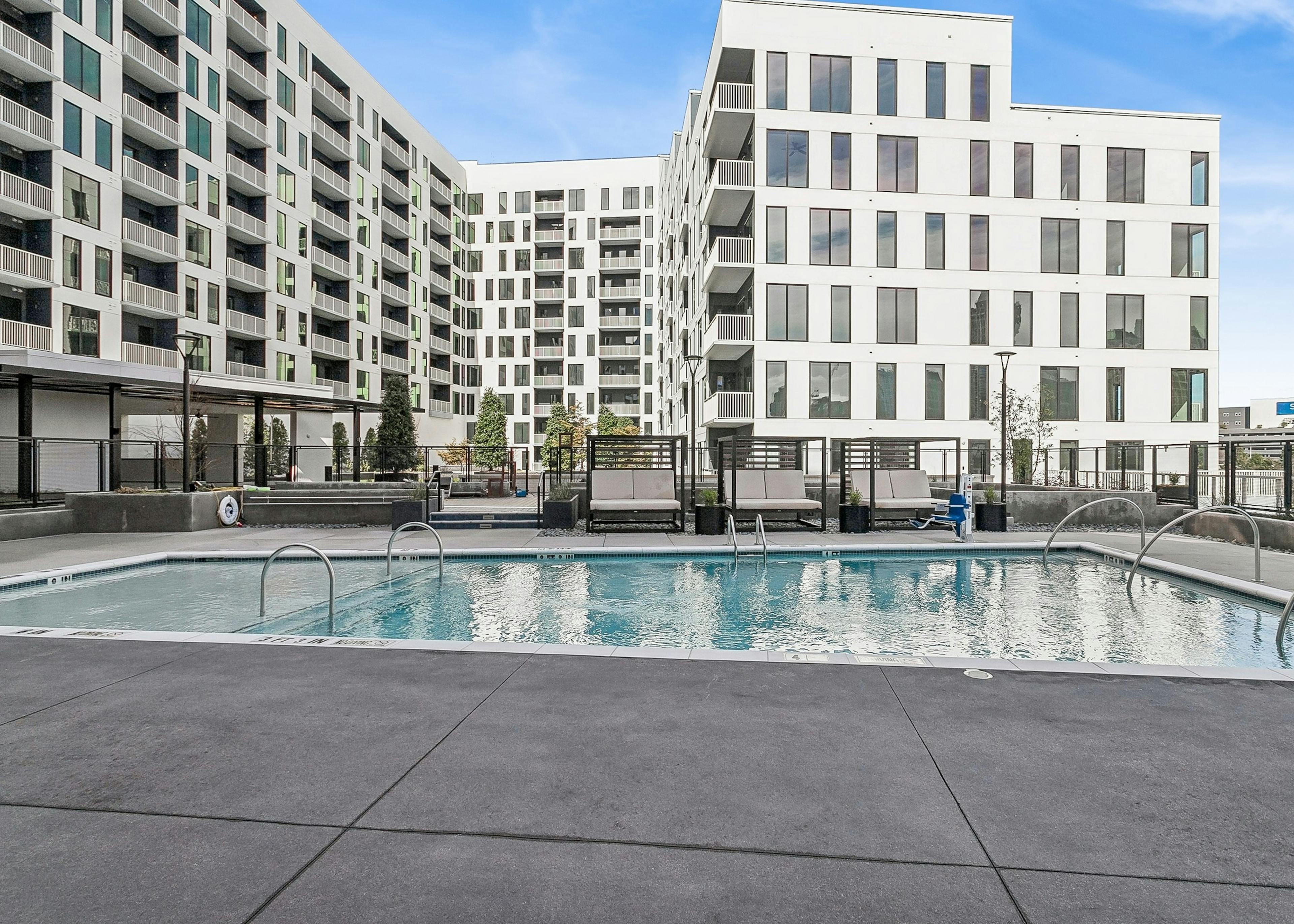 Outdoor pool area at AMLI Atlantic Station apartments with cabanas surrounded by white building with balconies