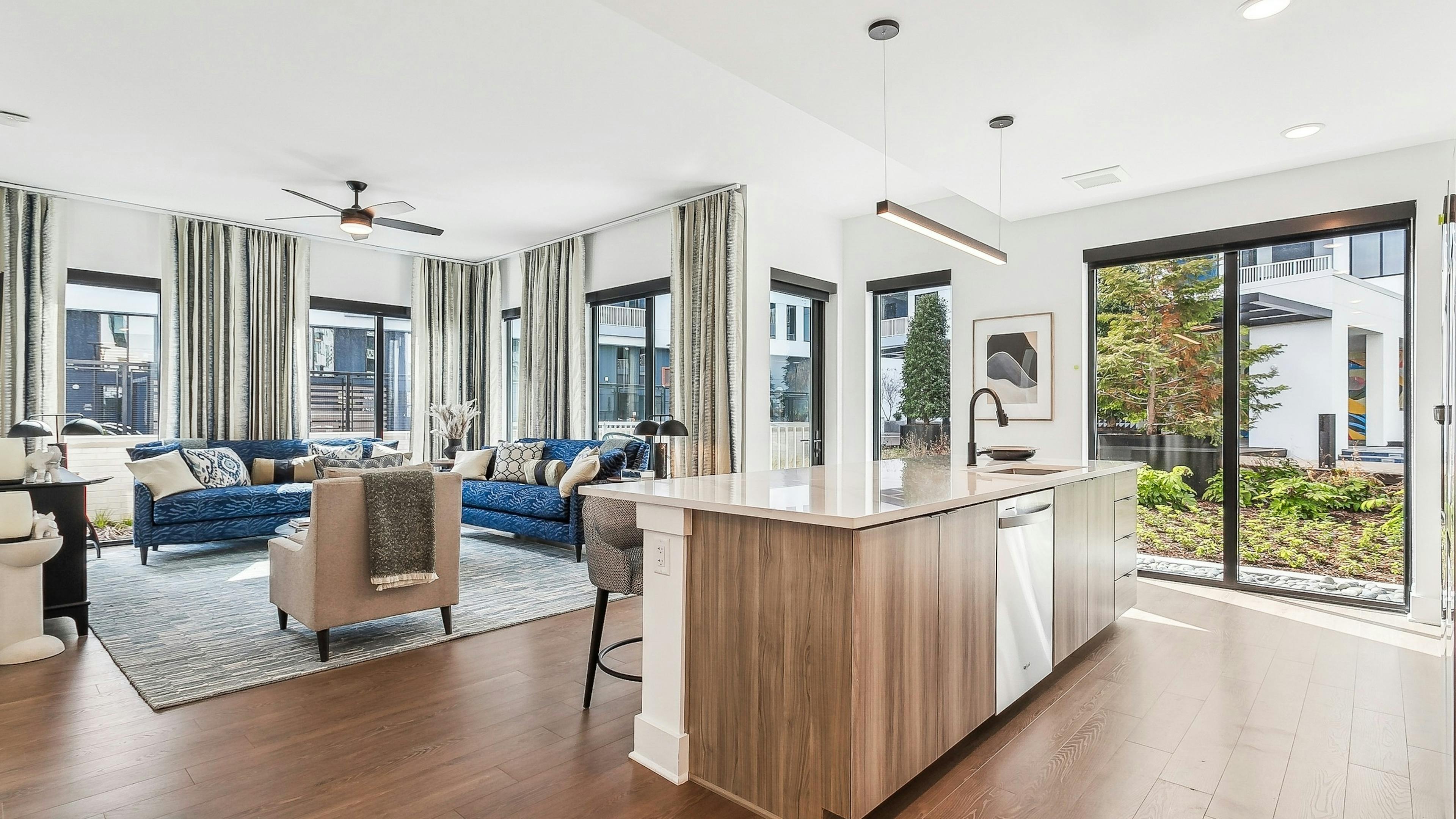 Open concept living room at AMLI Atlantic Station with hardwood floors and large windows with curtains and kitchen island