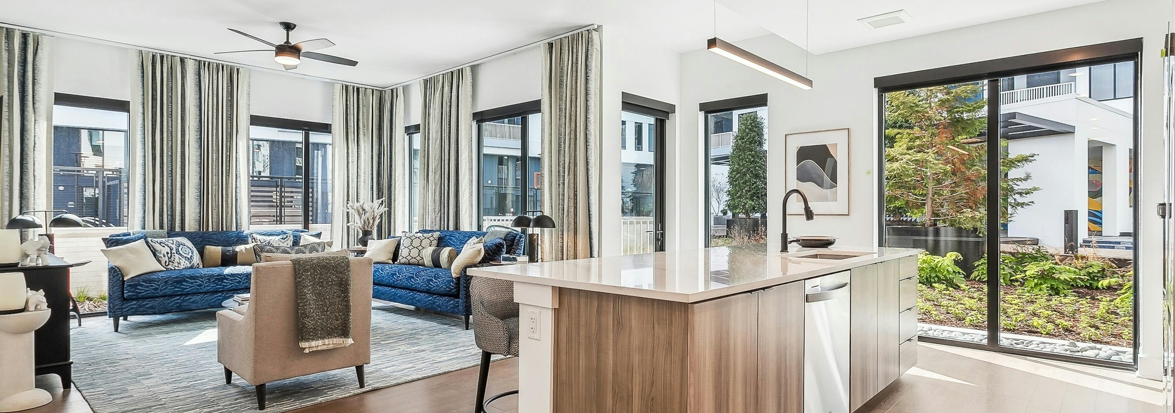 Open concept living room at AMLI Atlantic Station with hardwood floors and large windows with curtains and kitchen island