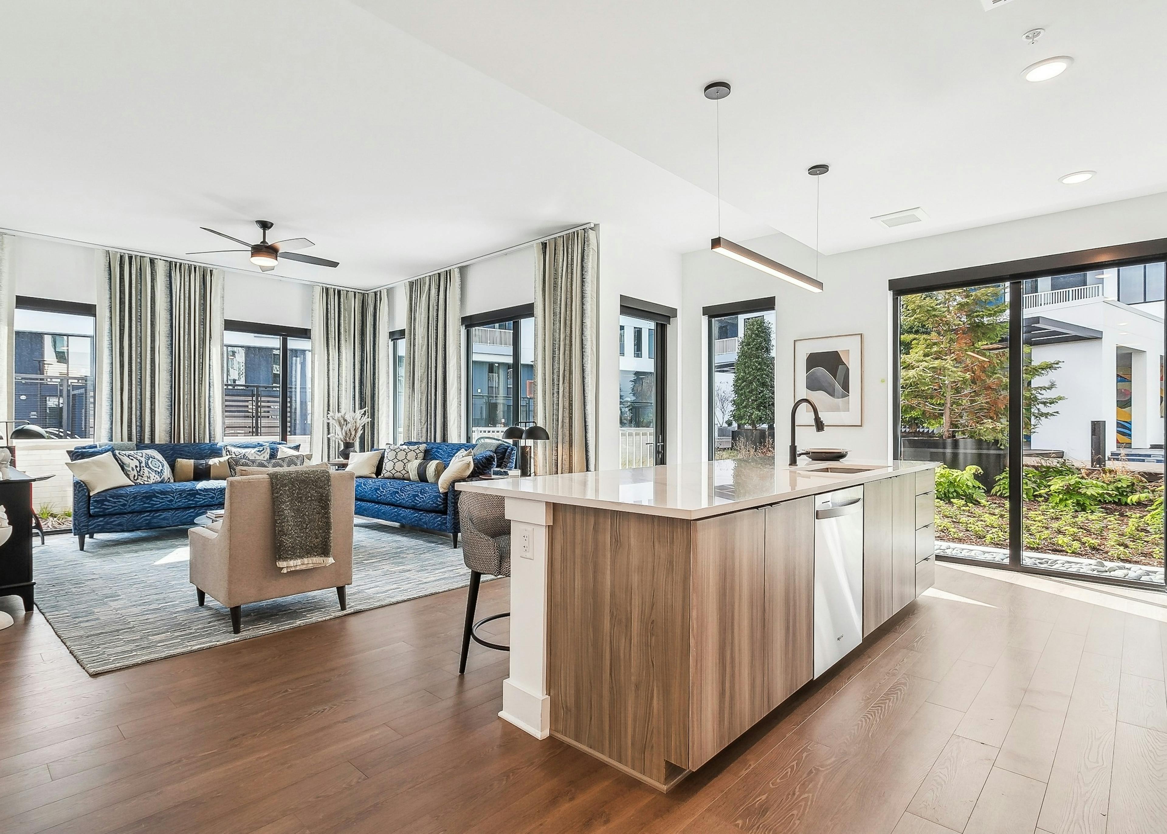 Open concept living room at AMLI Atlantic Station with hardwood floors and large windows with curtains and kitchen island