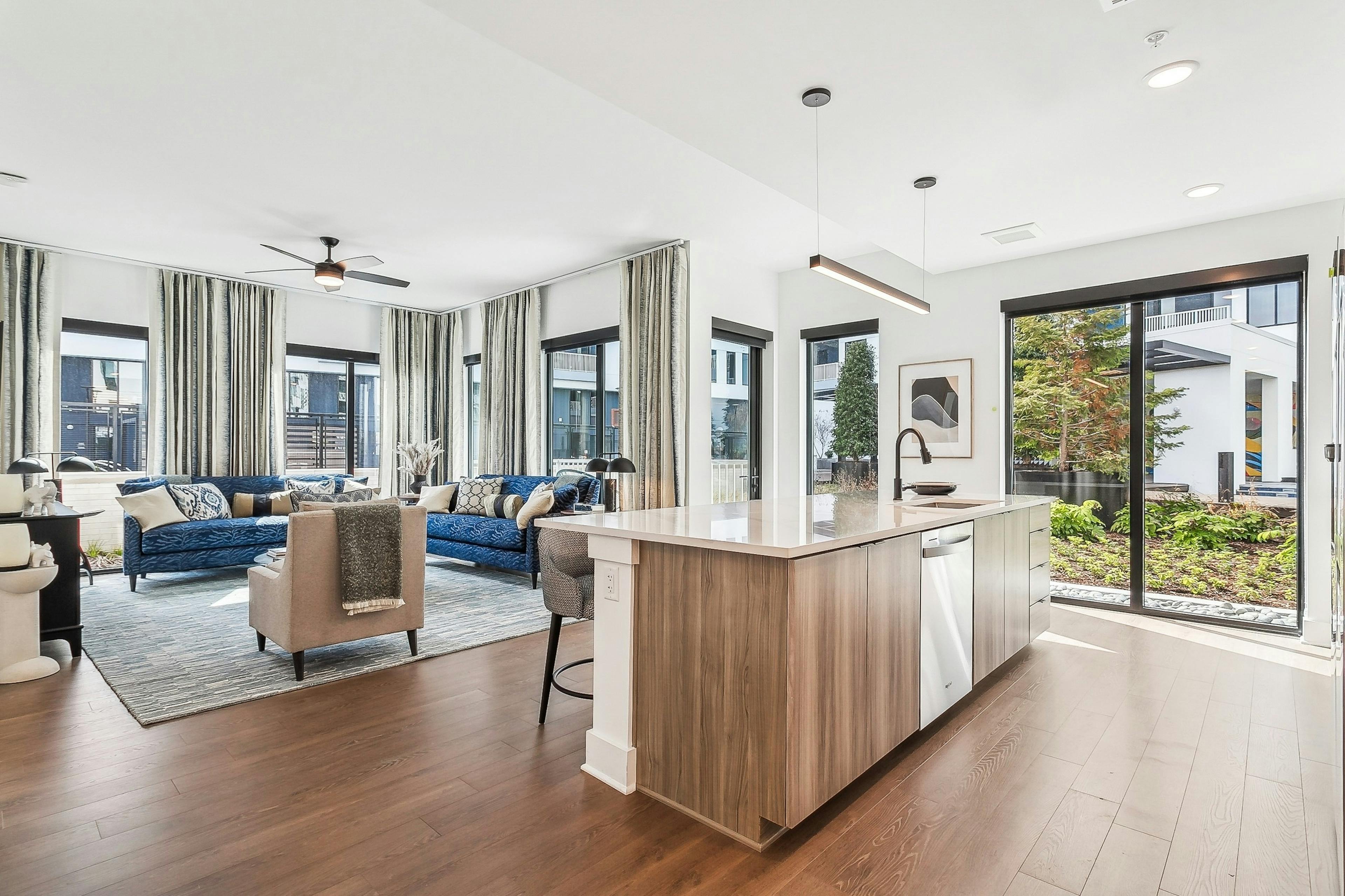 Open concept living room at AMLI Atlantic Station with hardwood floors and large windows with curtains and kitchen island