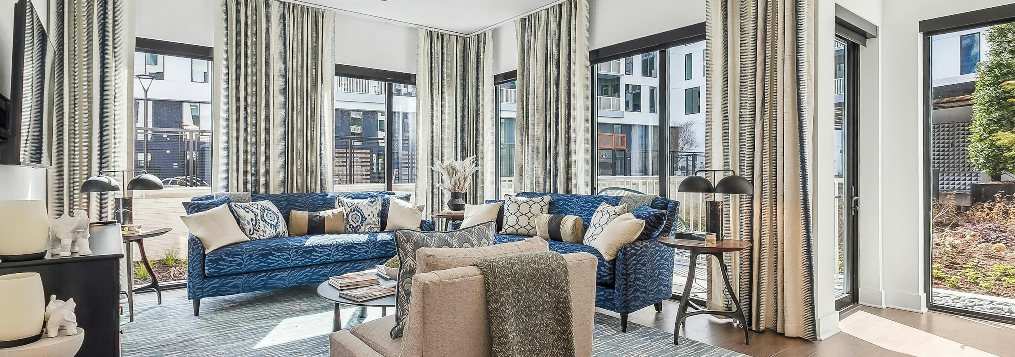 Living room at AMLI Atlantic Station apartments with large windows and navy blue couches and a beige armchair