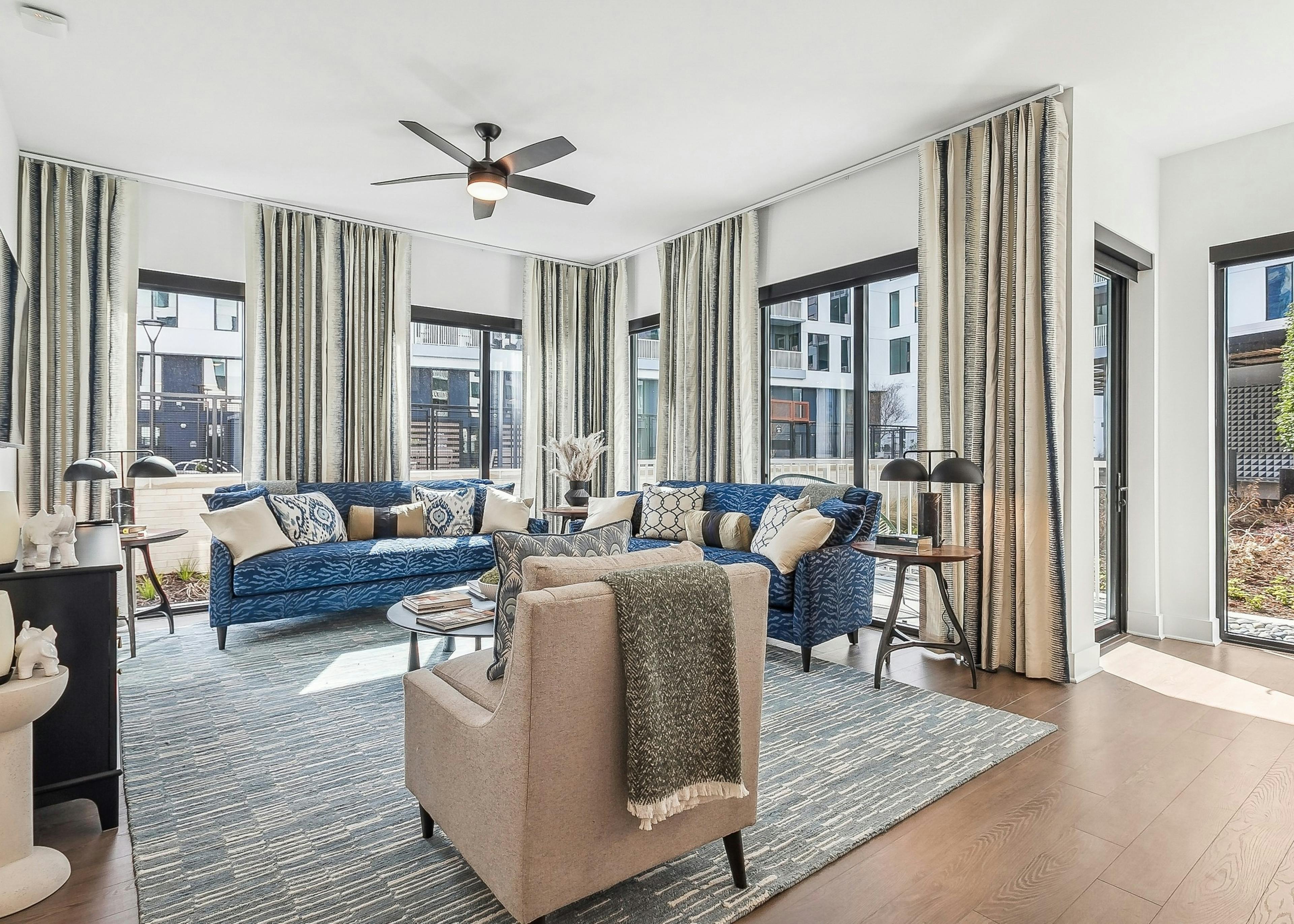 Living room at AMLI Atlantic Station apartments with large windows and navy blue couches and a beige armchair