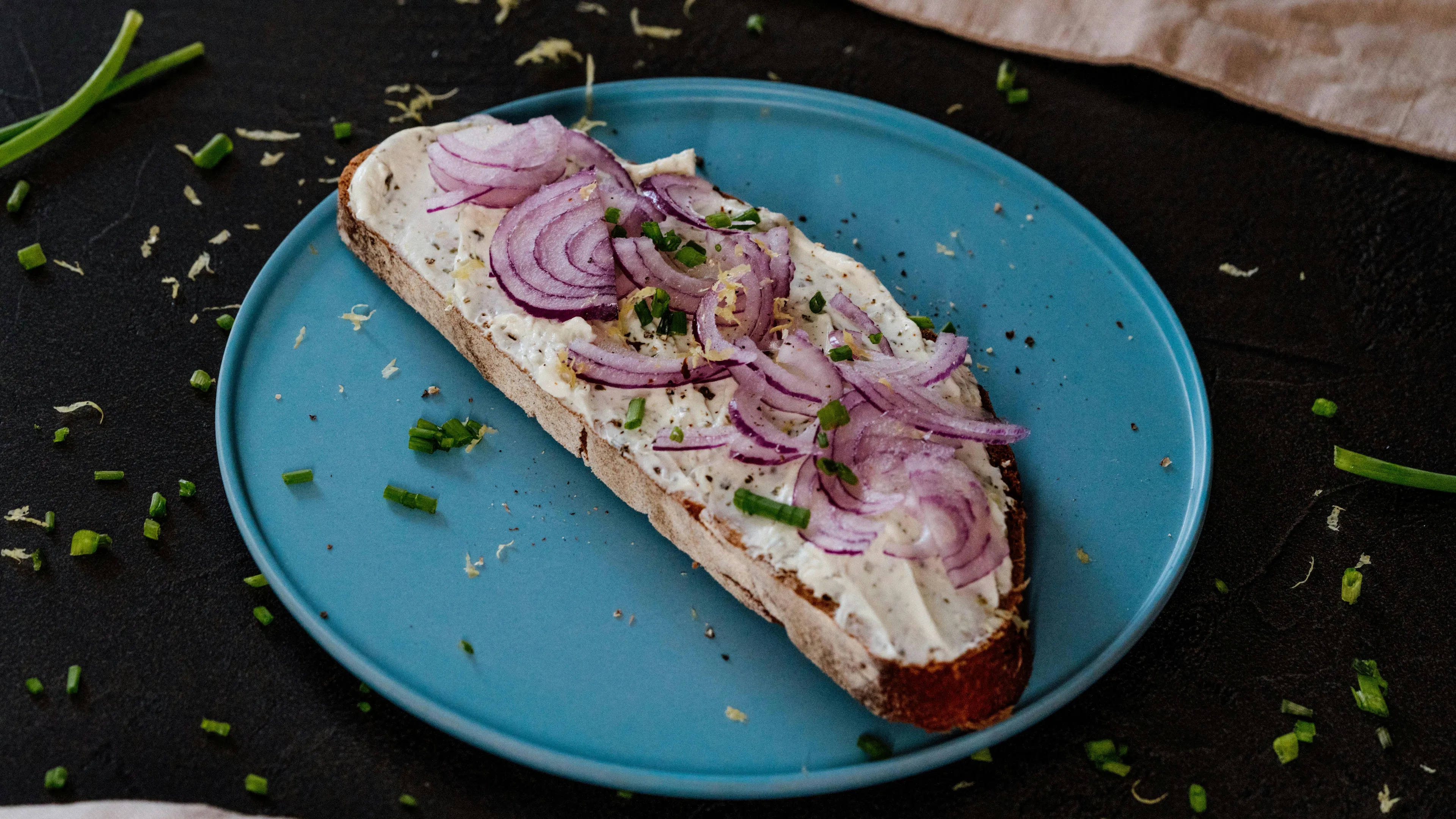 A Danish open faced sandwich made with rye bread and topped with red onions and cream cheese