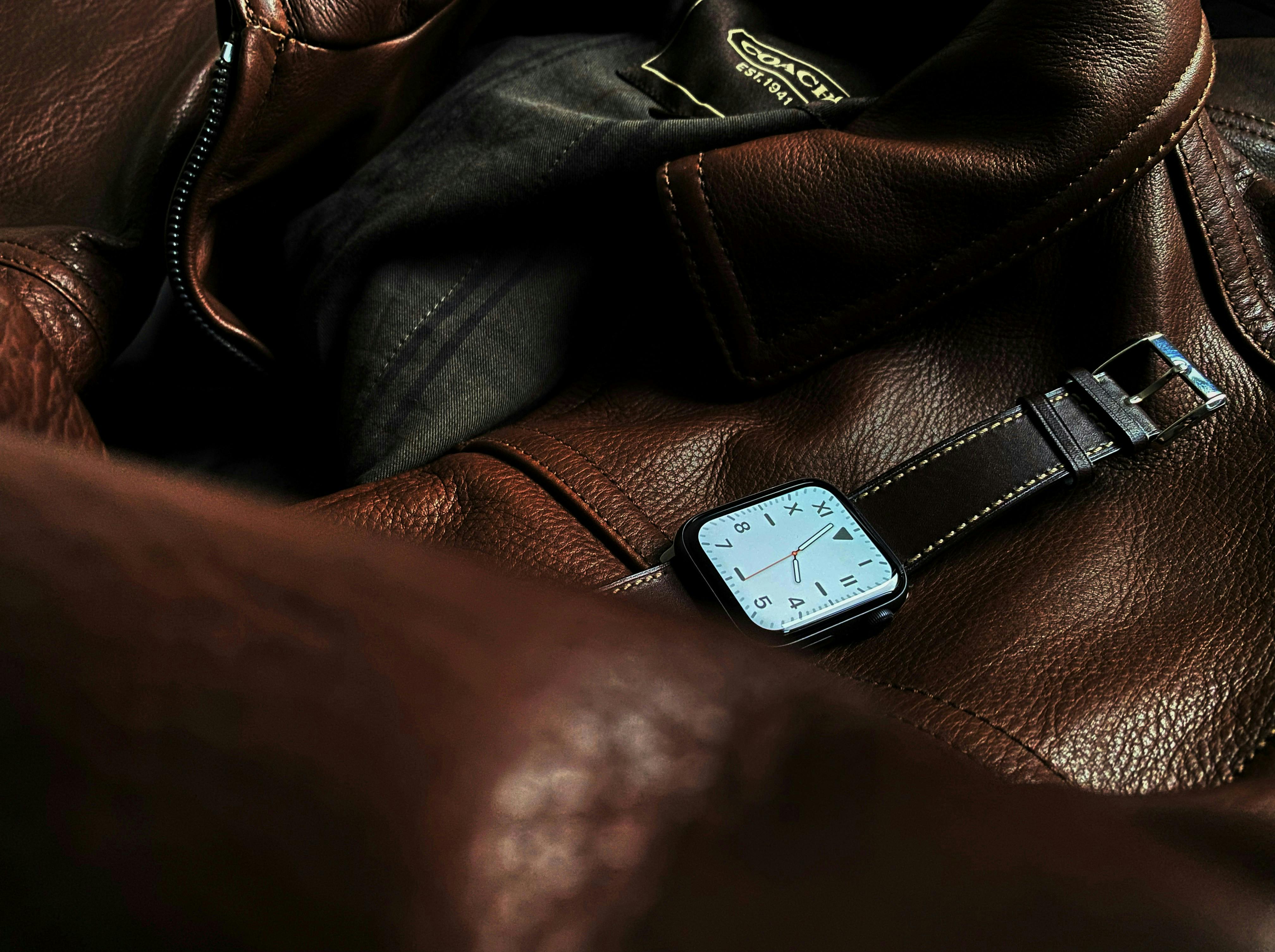 A stylish watch with a leather strap resting on a brown leather jacket