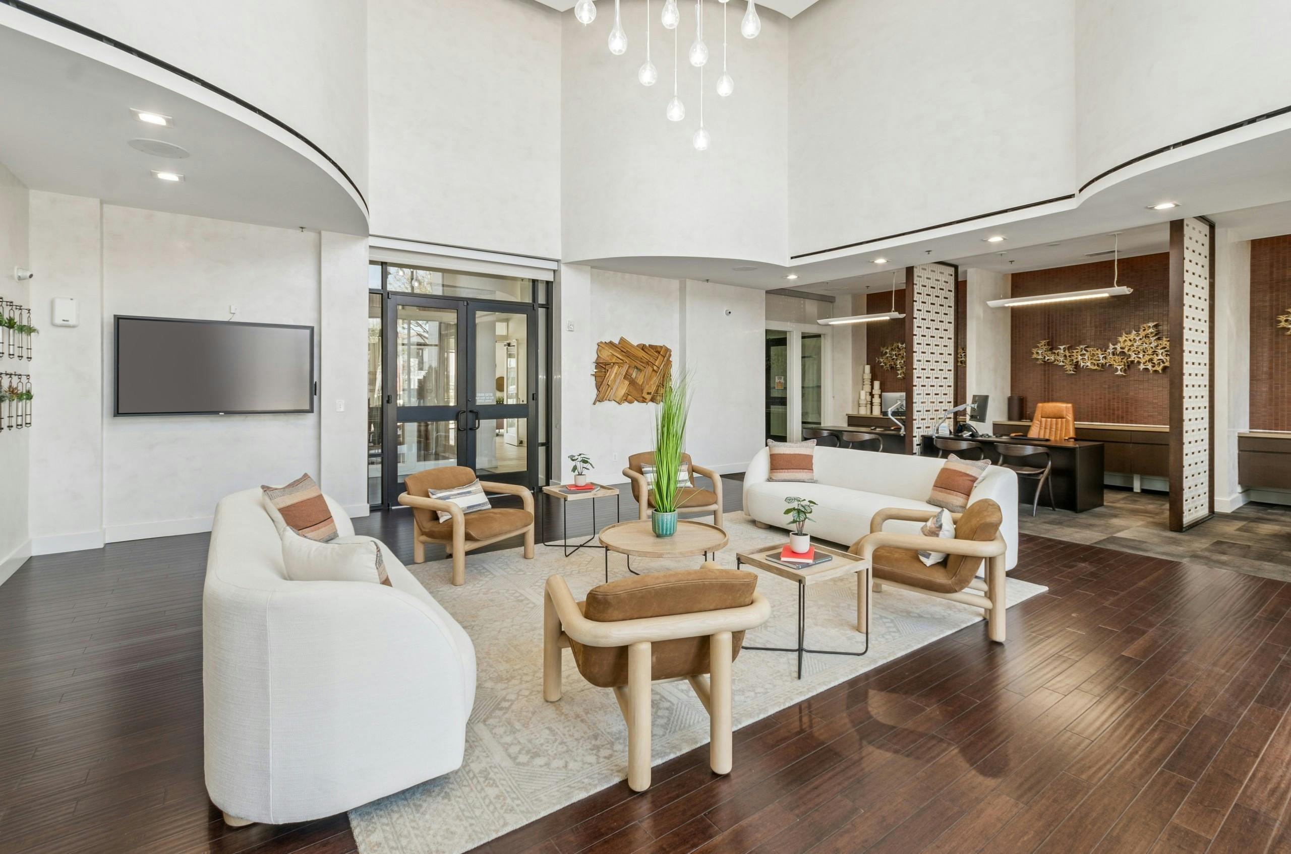 AMLI on Riverside modern leasing lounge with white walls, a seating area with sofas, armchairs, a round coffee table on wood floors