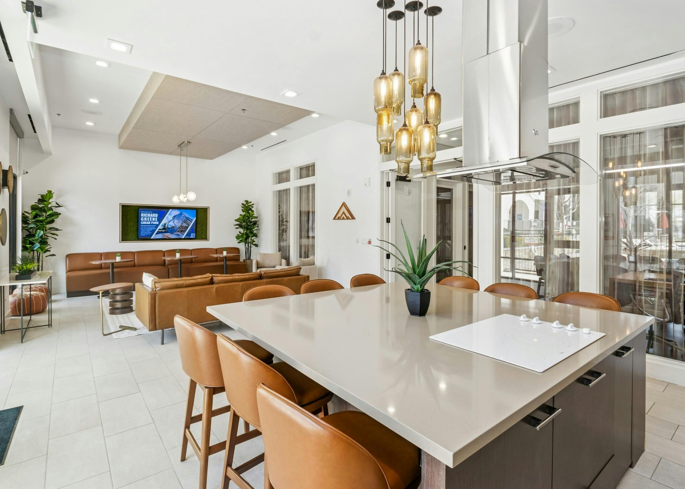 Resident kitchen and lounge with a large island, leather stools adjacent to leather couches and TV at AMLI on Riverside apartments