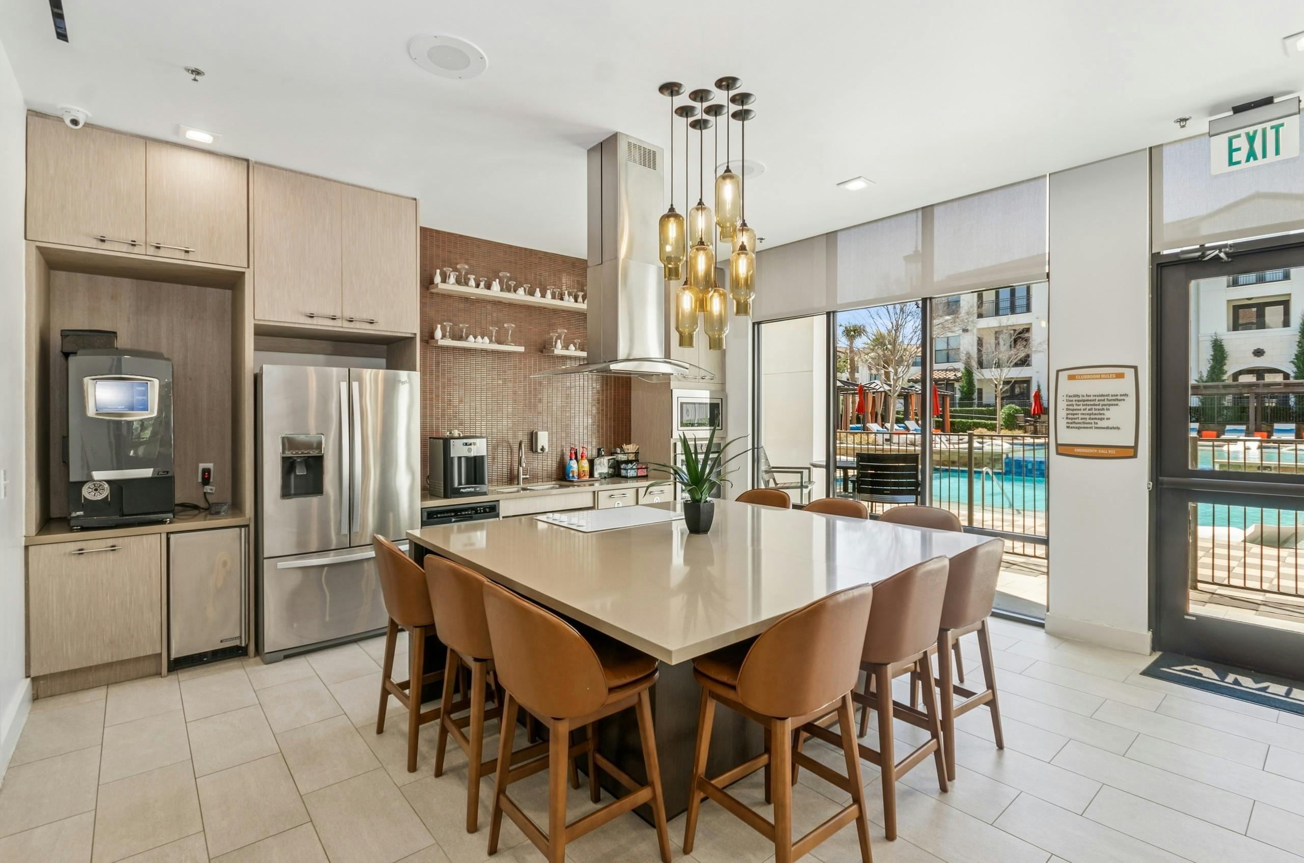Resident kitchen with a large island and eight brown chairs, stainless steel appliances and light wood cabinets at AMLI on Riverside