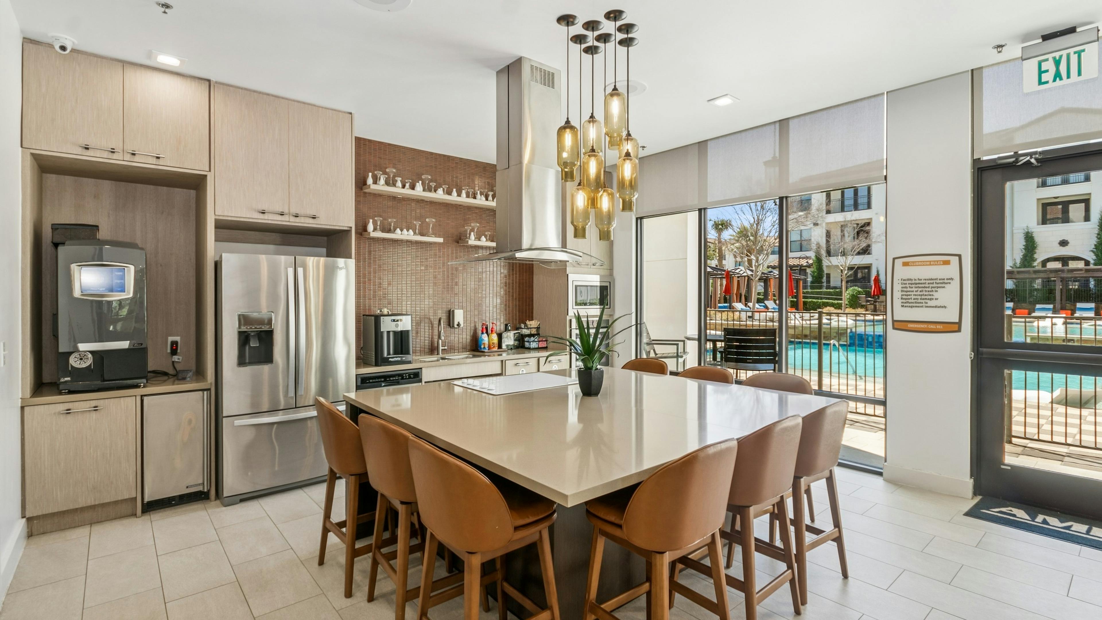 Resident kitchen with a large island and eight brown chairs, stainless steel appliances and light wood cabinets at AMLI on Riverside