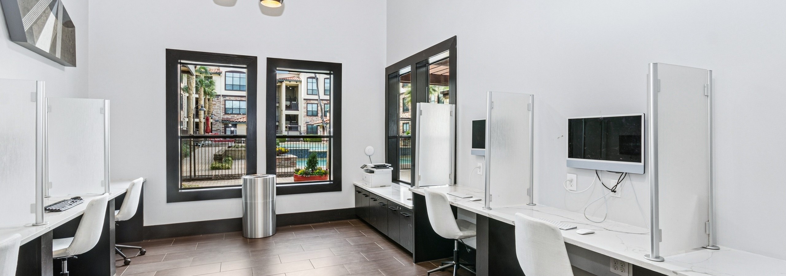 AMLI at Escena business center with large windows and white computer stations and chairs separated by glass partitions