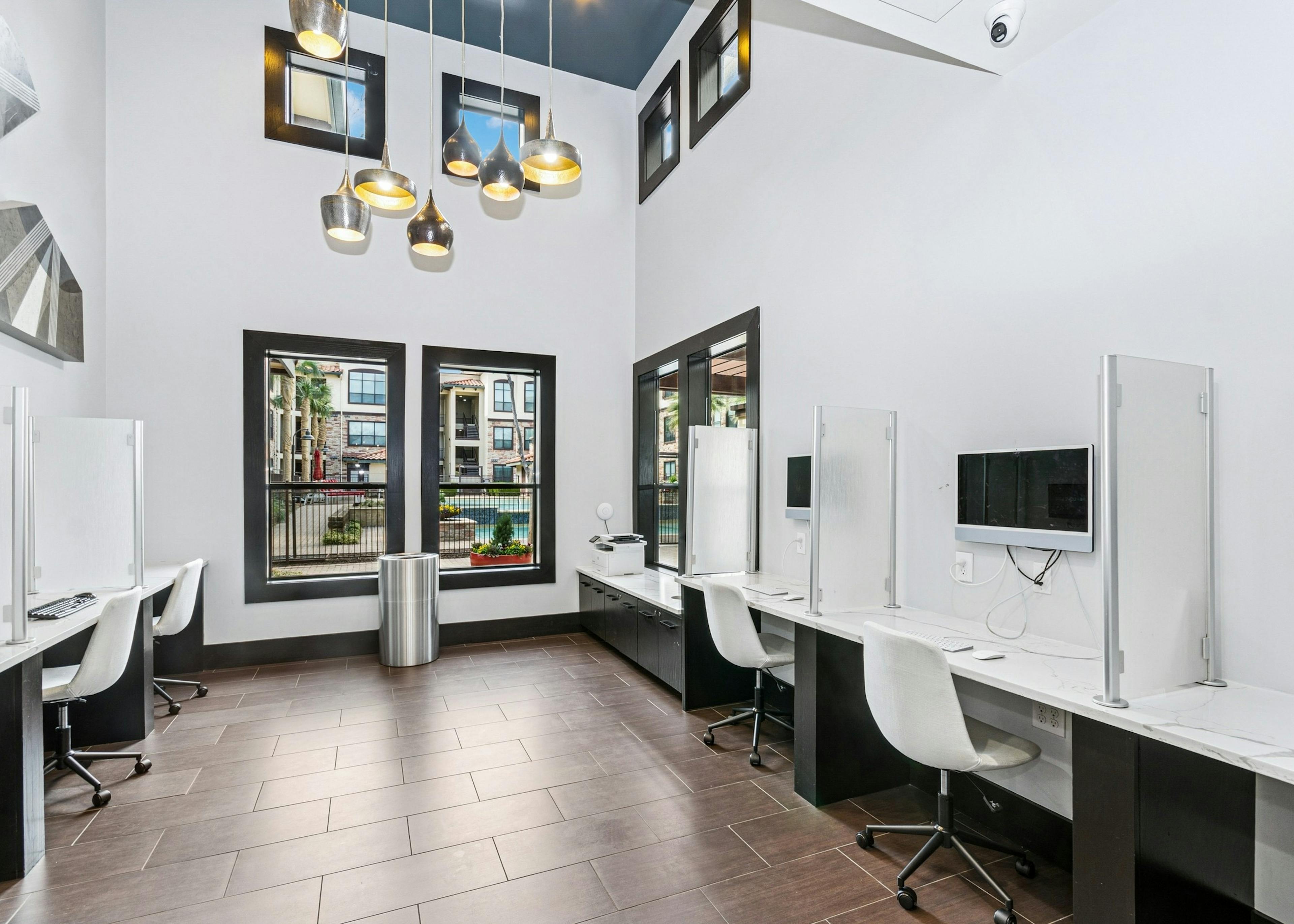 AMLI at Escena business center with large windows and white computer stations and chairs separated by glass partitions