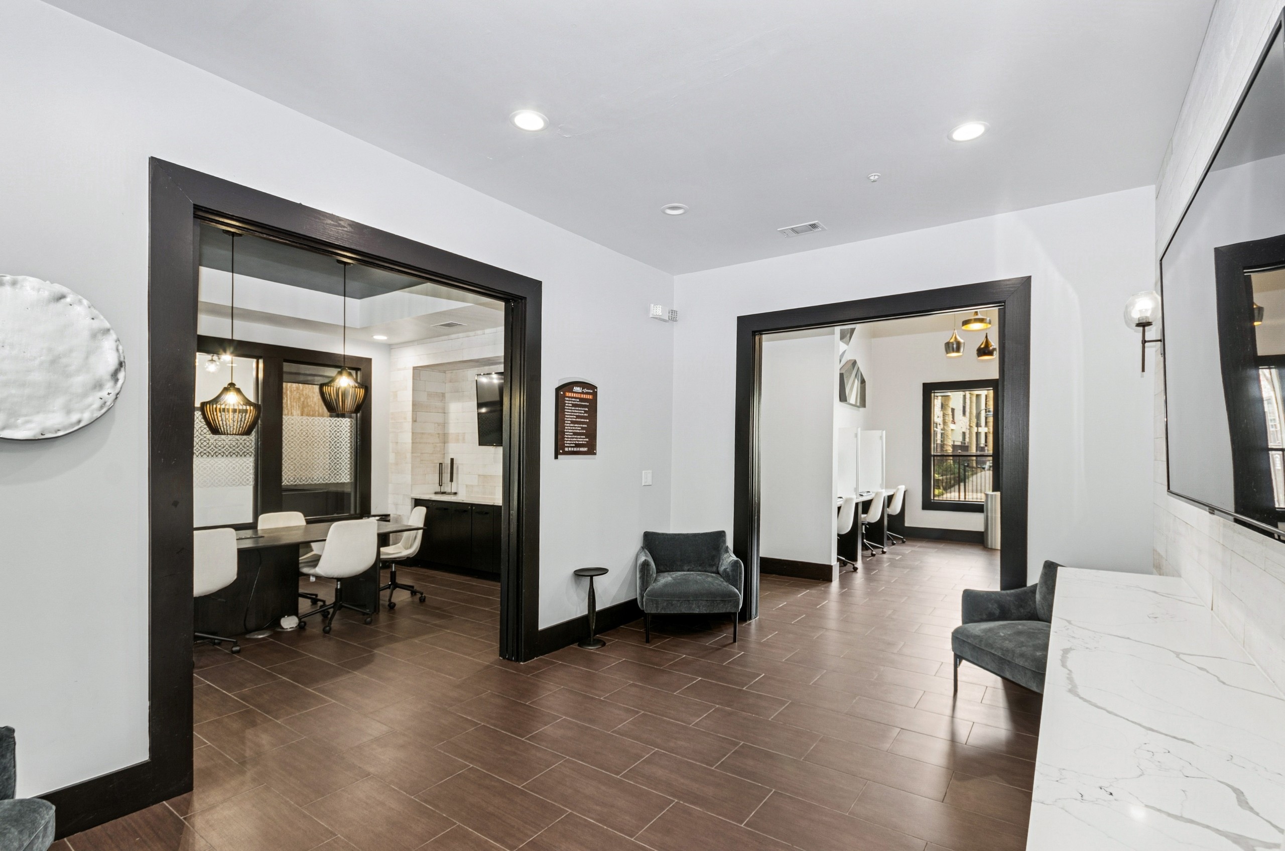 Modern business lounge with wood floors, light gray walls and views into conference room and business center at AMLI at Escena apartments