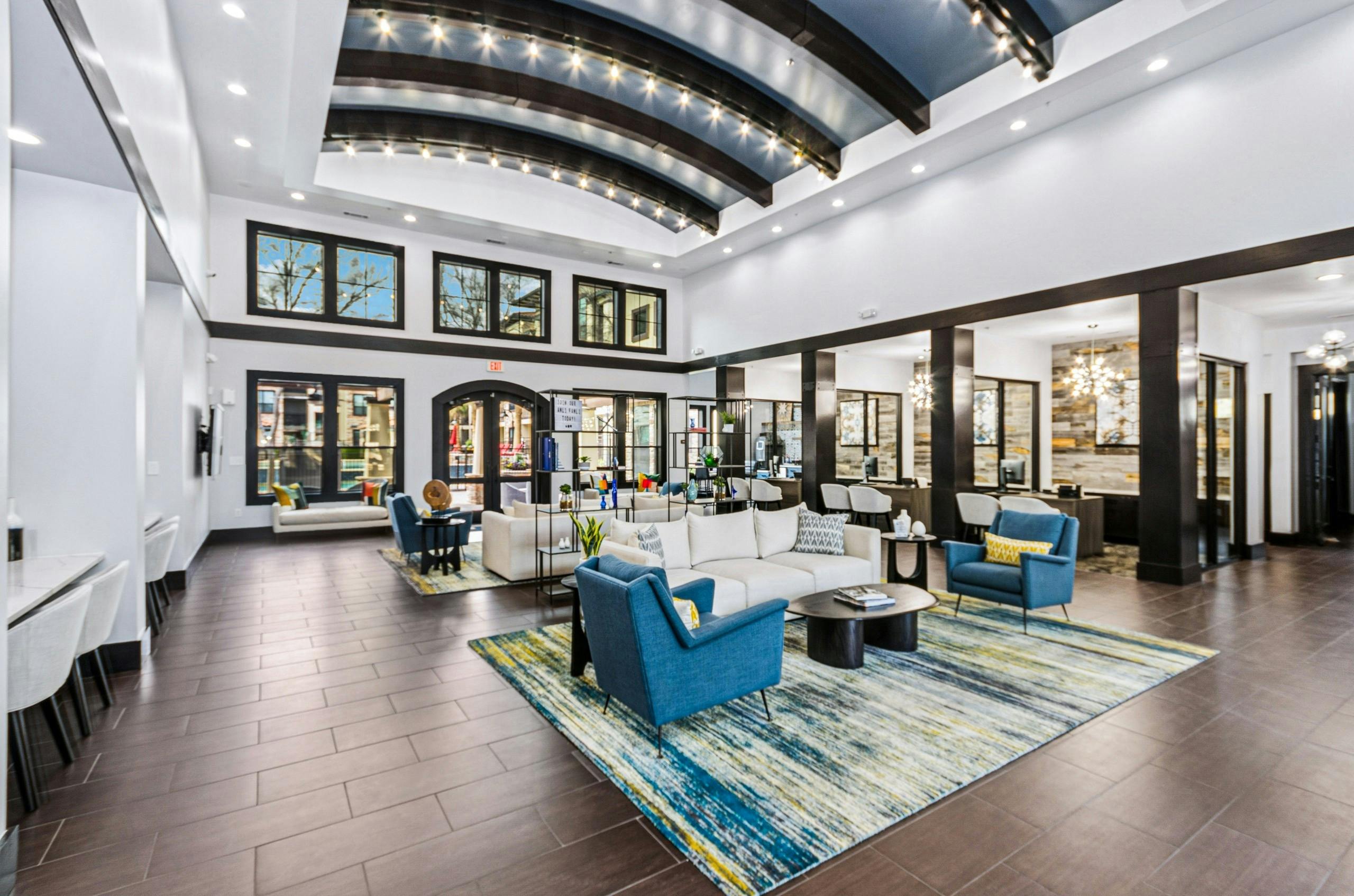 AMLI at Escena apartments leasing office and clubhouse with bright blue chairs, beige sofas, colorful rug and large windows