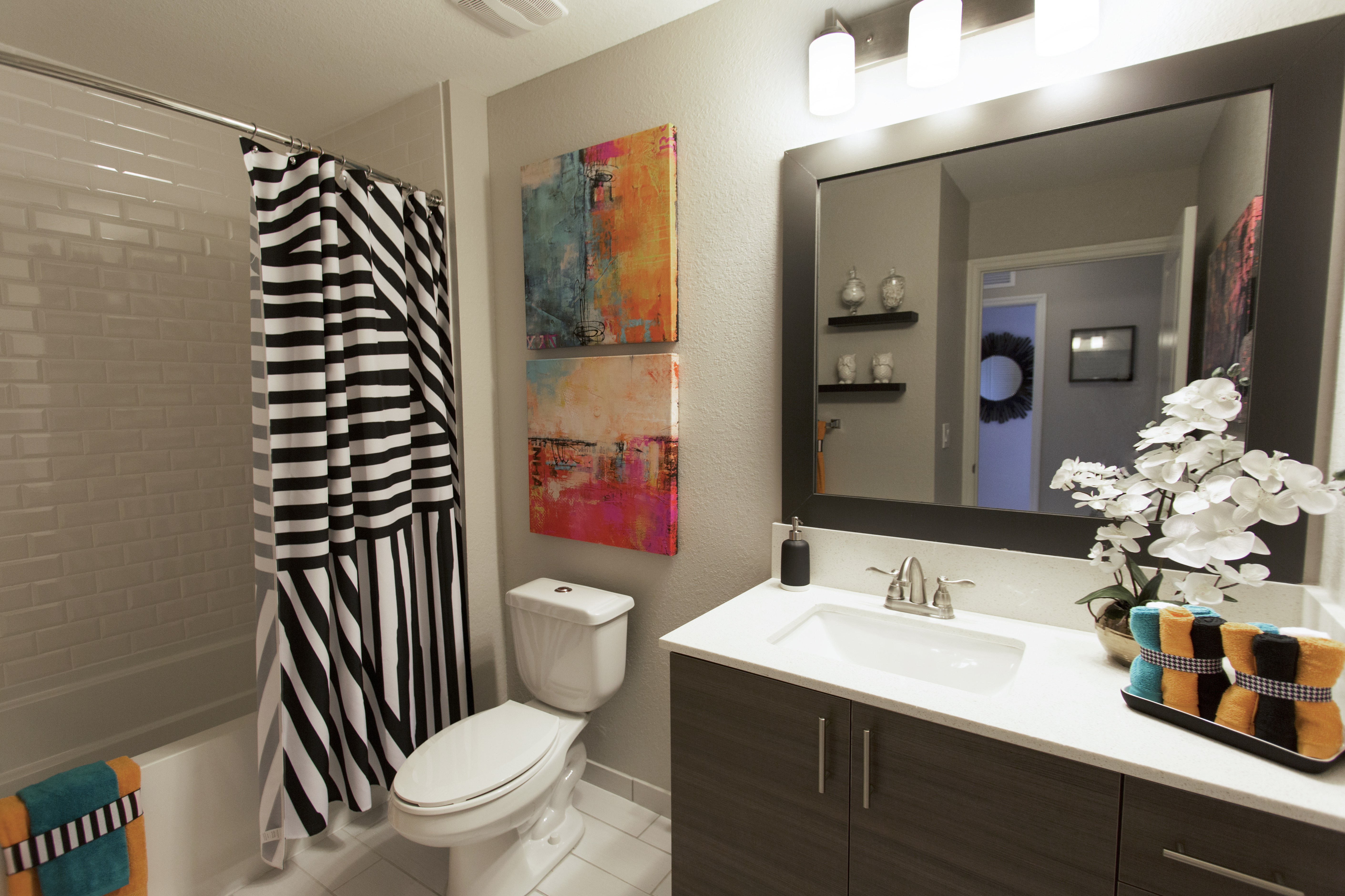 Interior view of bathroom at AMLI Dadeland apartments with single sink vanity, mirror and black and white shower curtain