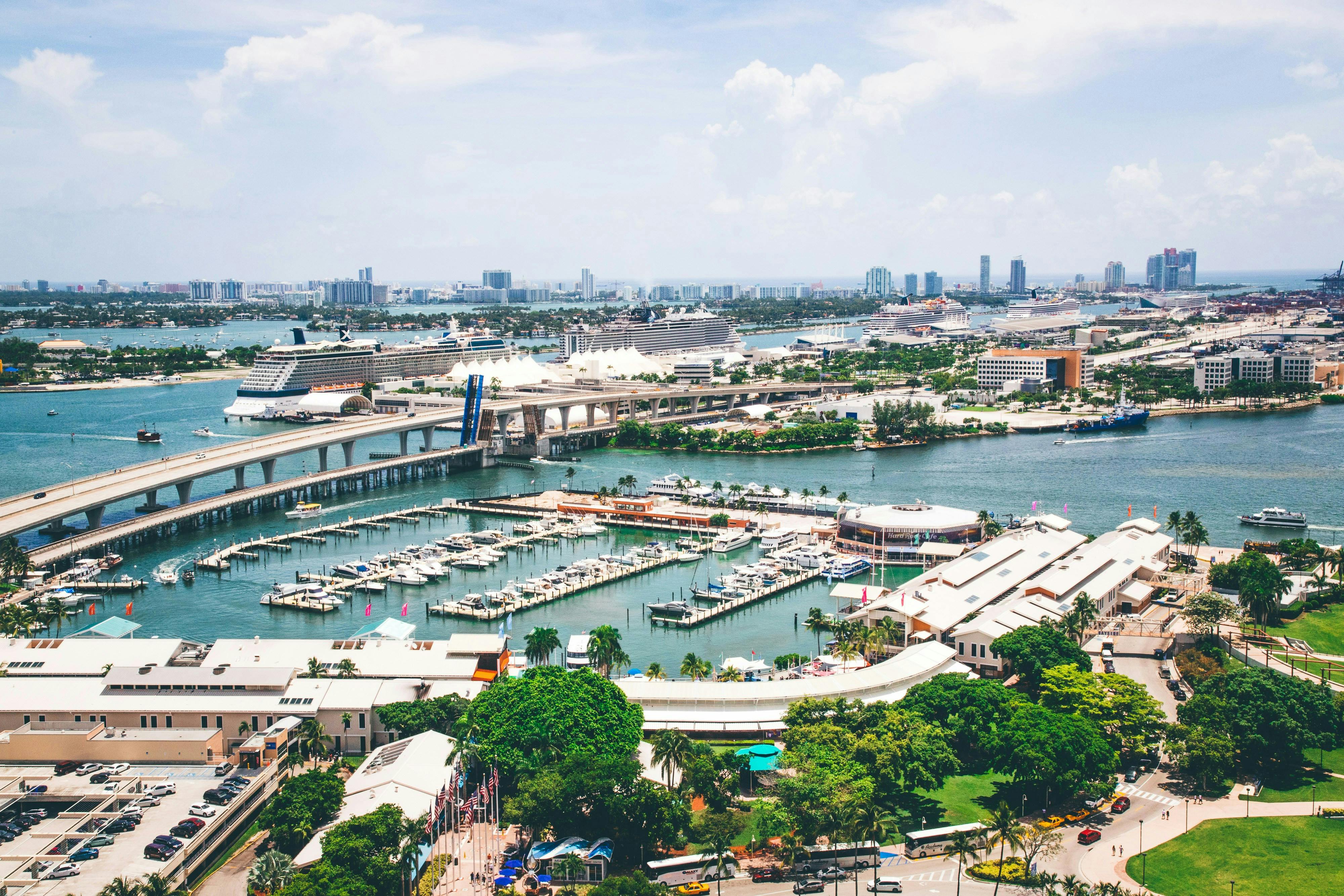 An aerial shot of a boat marina next to a bridge on a sunny day