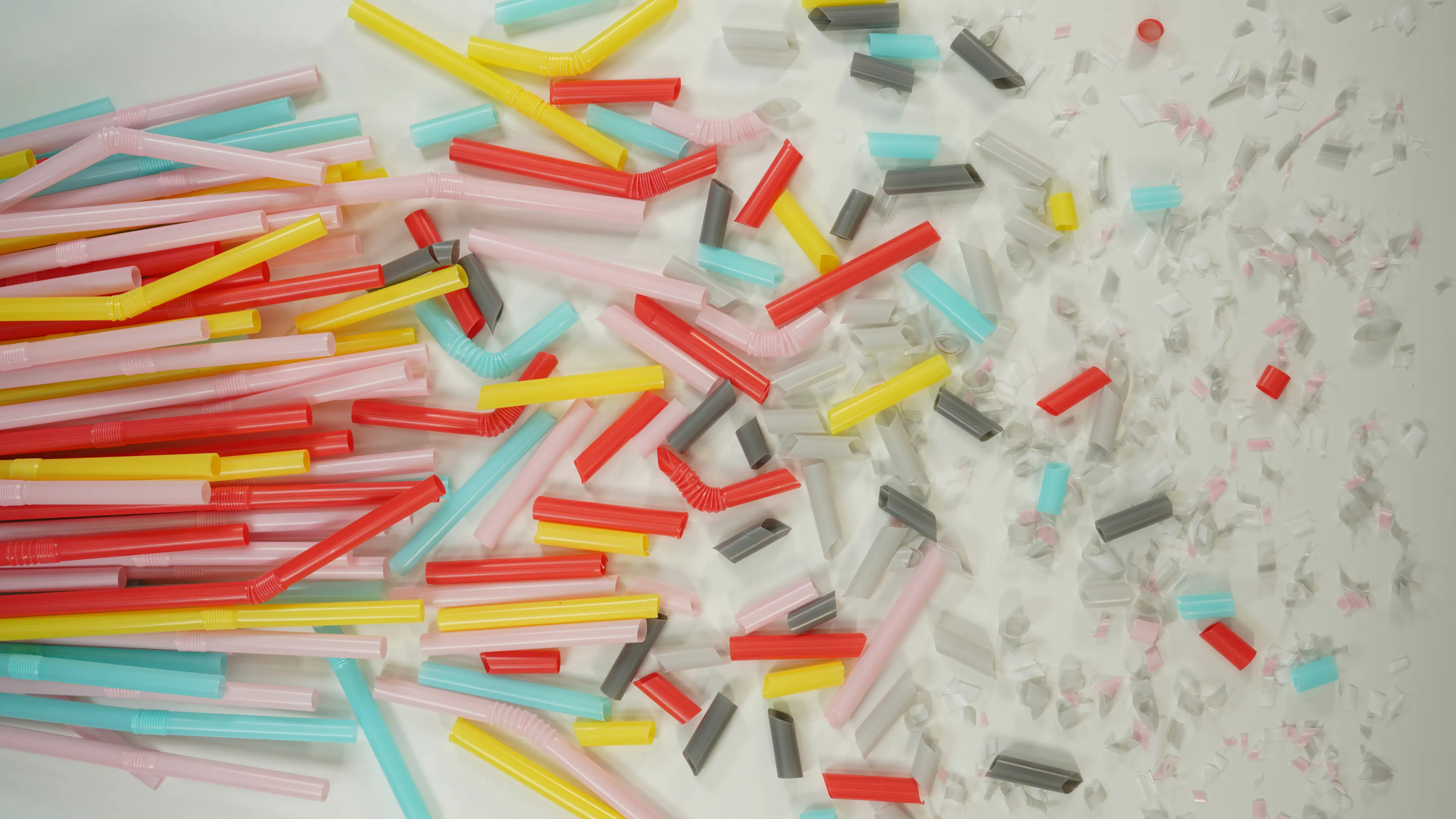 A bunch of colorful plastic straws on a table with the tips cut into many small pieces