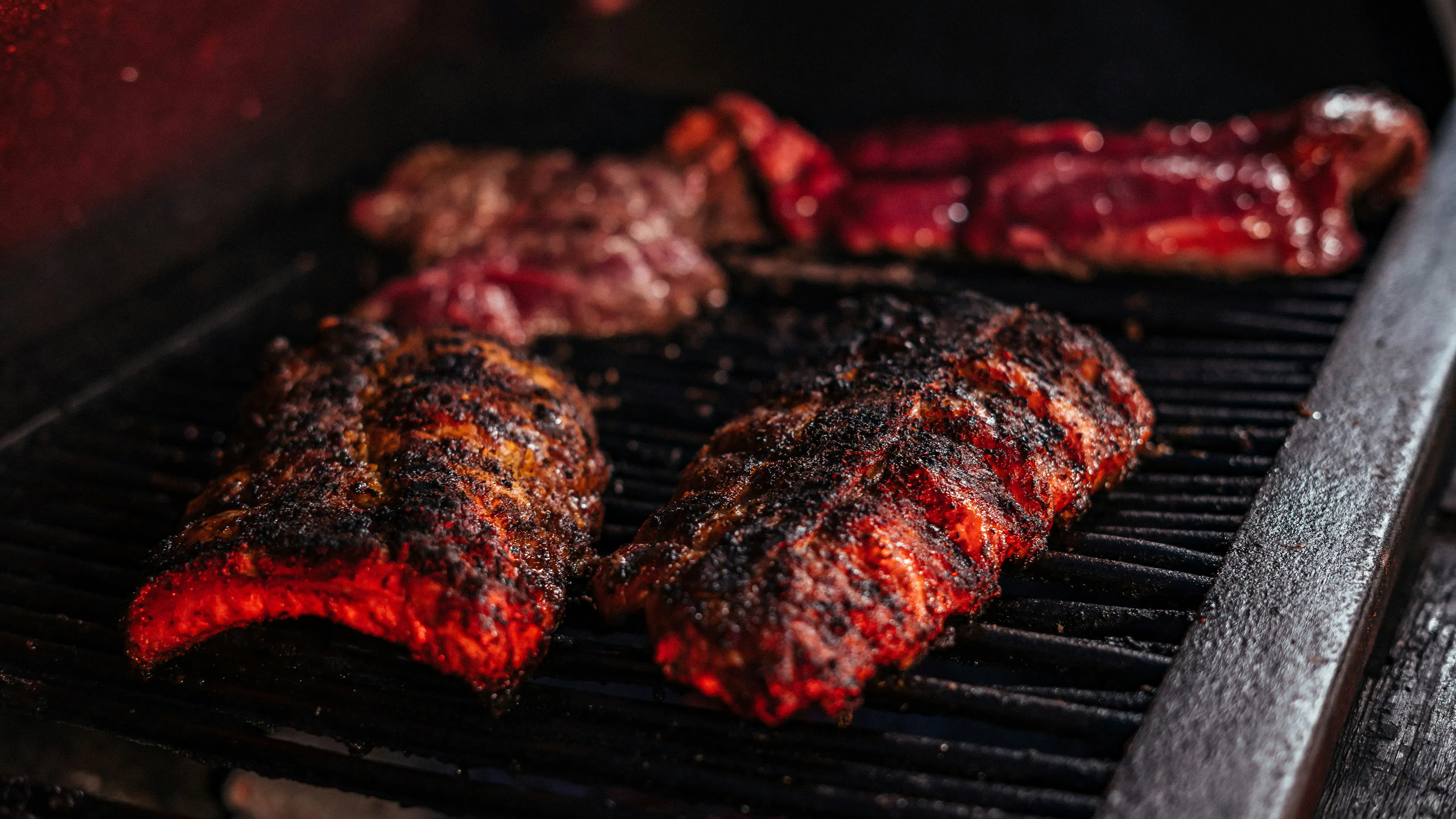 A few racks of ribs cooking over a metal grill