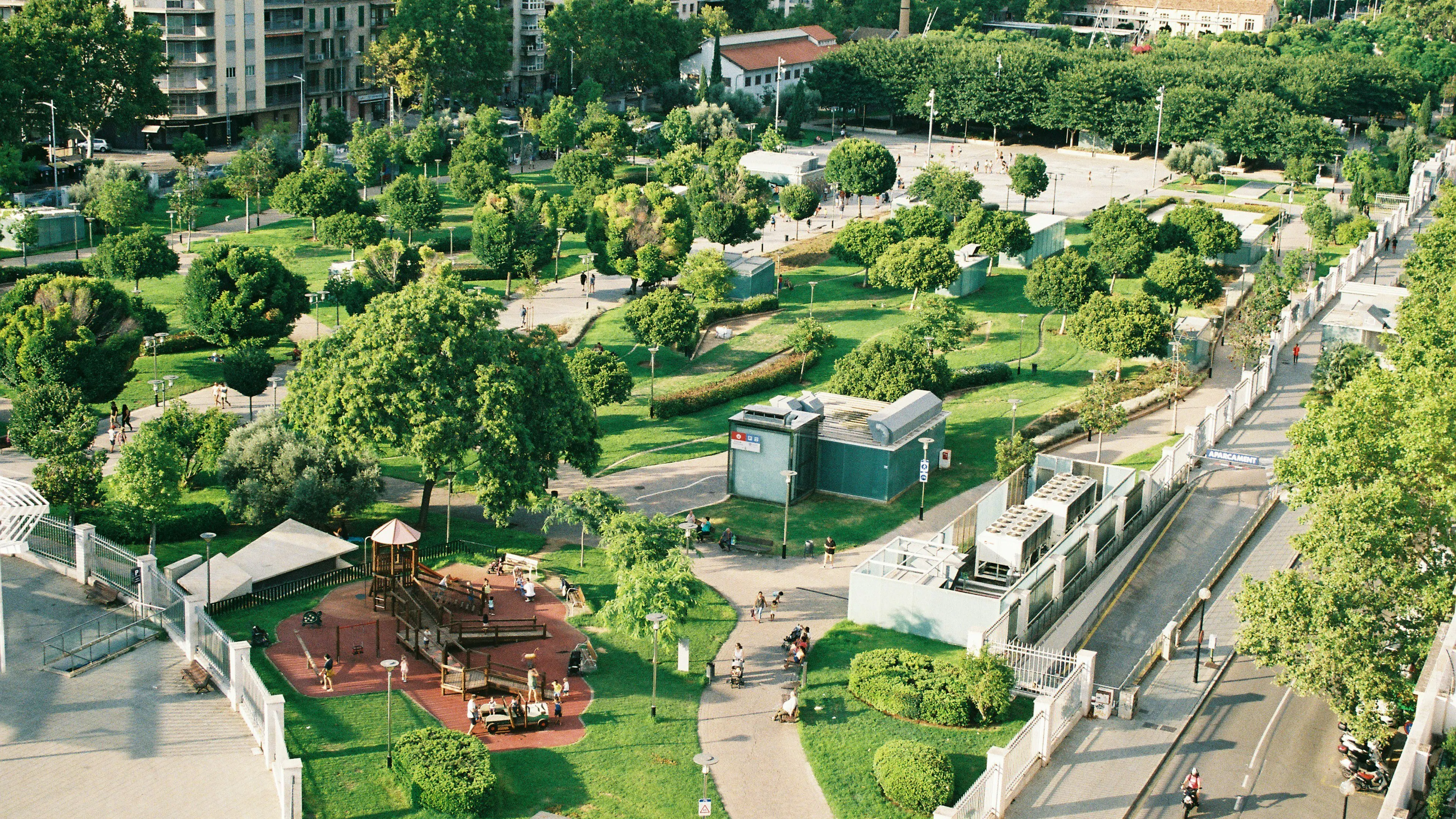 An elaborate city park with playgrounds and sidewalks and lawns surrounded by tall buildings