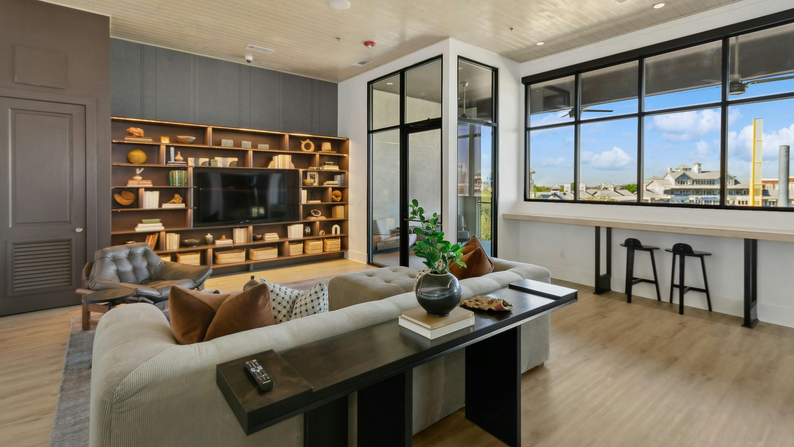 Sky lounge media room with a large window and a shelving unit surrounding a flat screen tv and cozy seating area at AMLI at the Ballpark