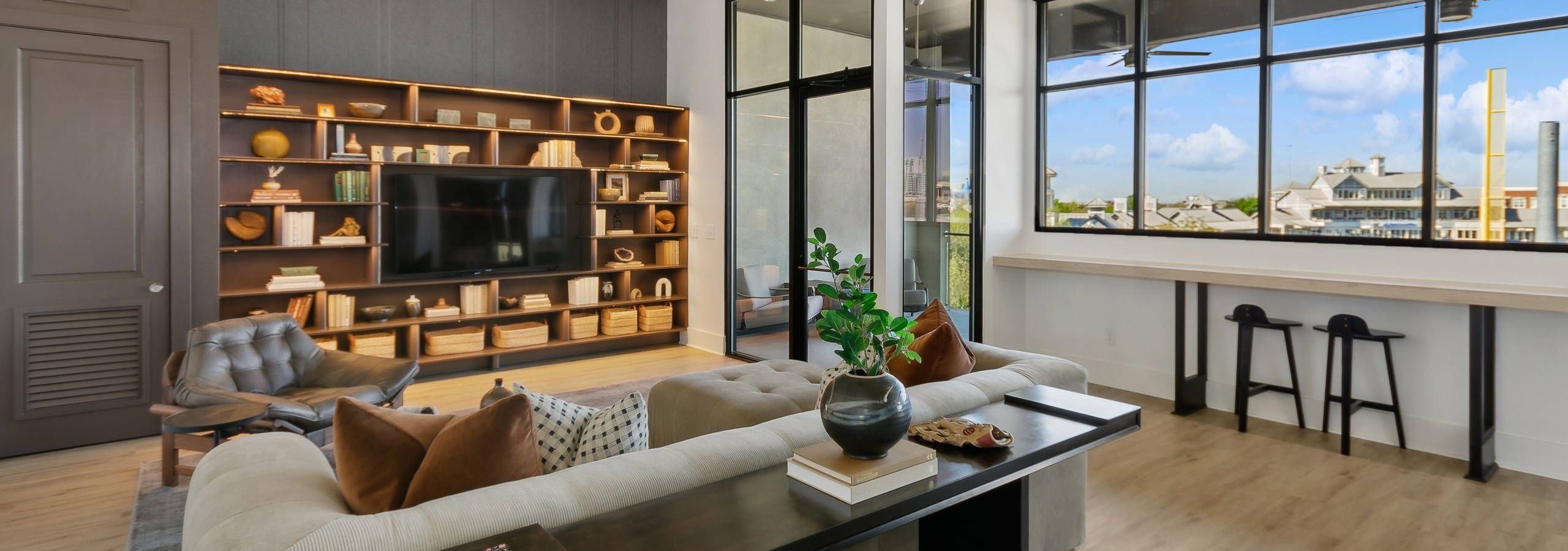 Sky lounge media room with a large window and a shelving unit surrounding a flat screen tv and cozy seating area at AMLI at the Ballpark