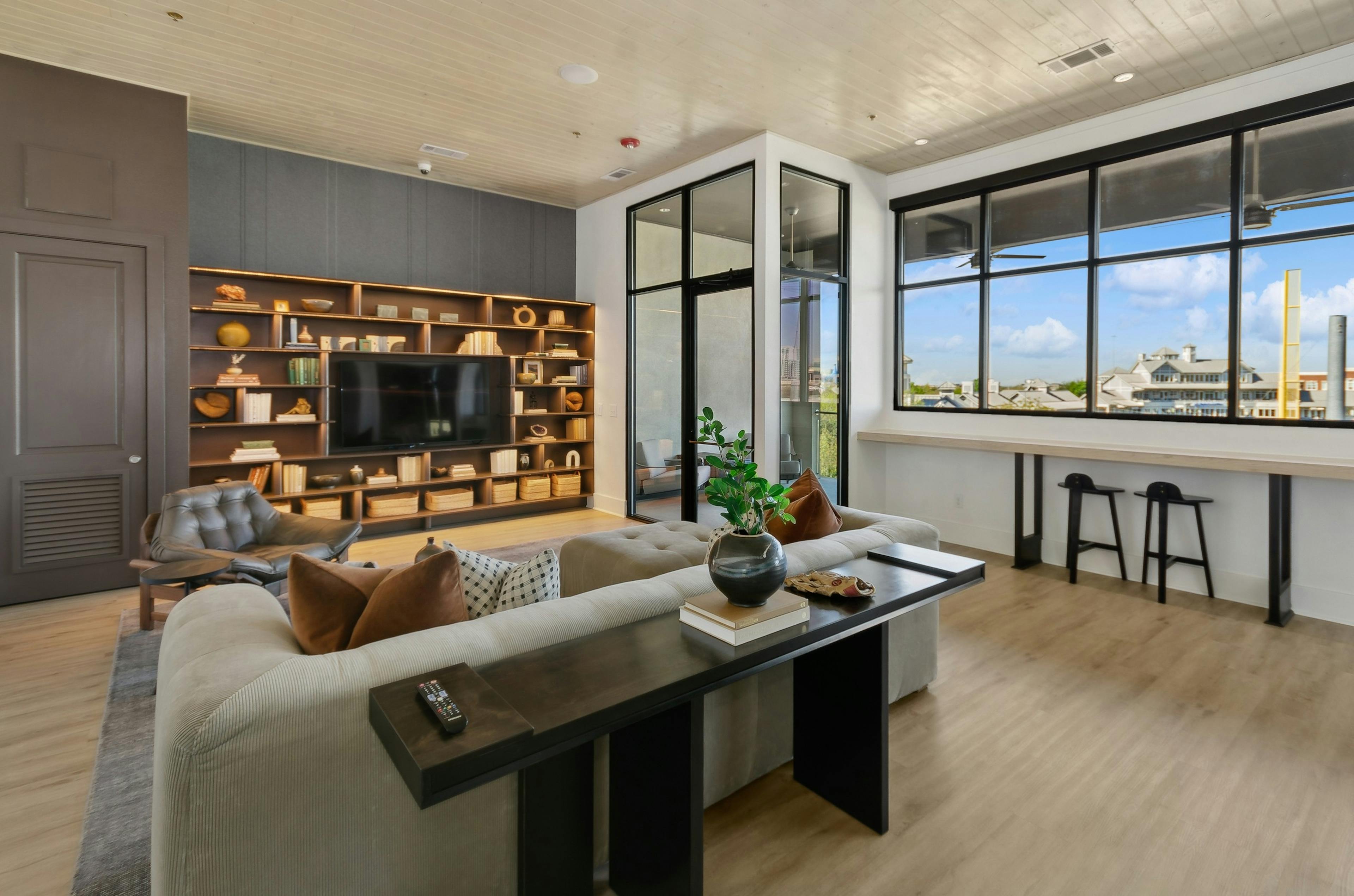 Sky lounge media room with a large window and a shelving unit surrounding a flat screen tv and cozy seating area at AMLI at the Ballpark 