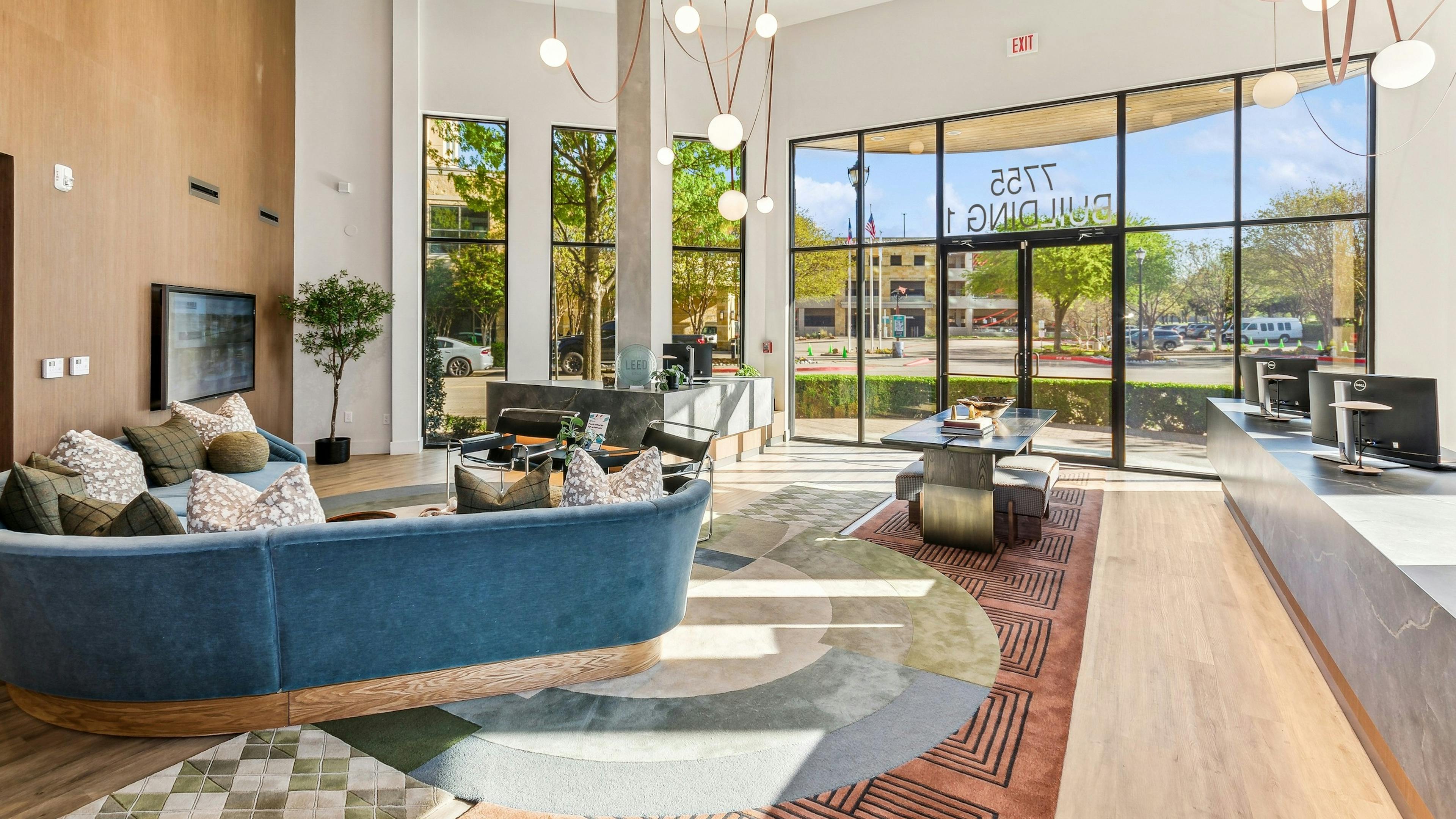 AMLI at the Ballpark lobby with blue sofa and touch screen tv and computer stations and entry table near door and oversized windows