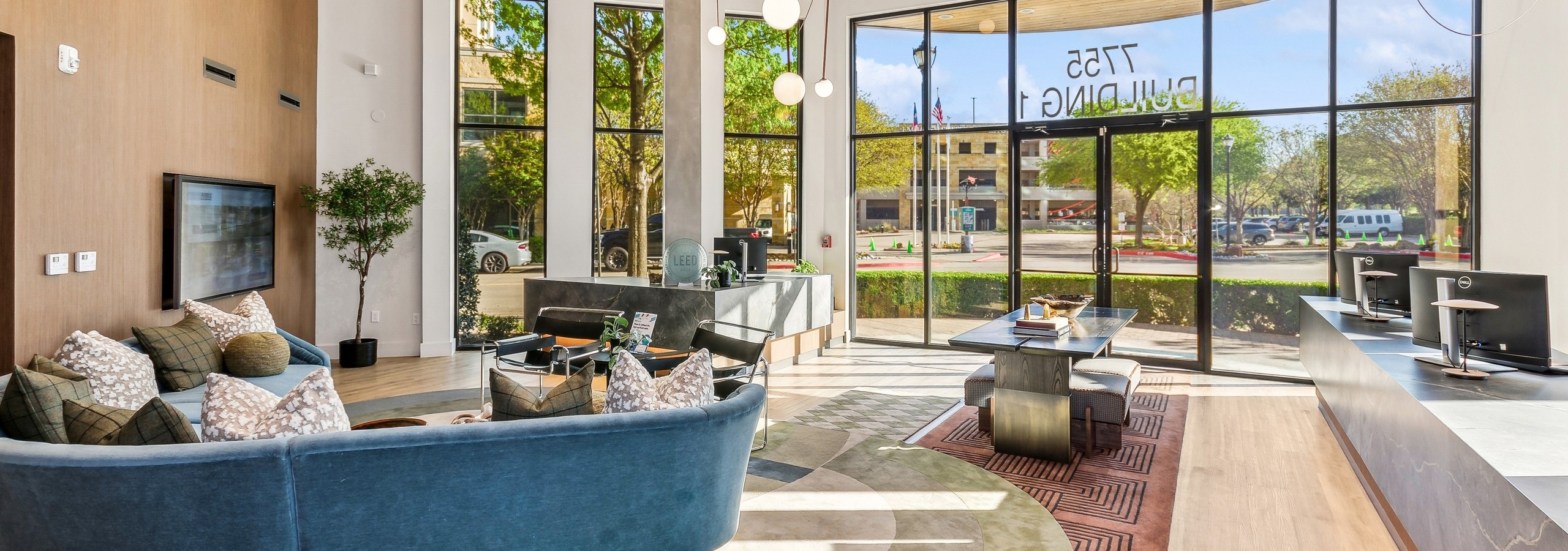 AMLI at the Ballpark lobby with blue sofa and touch screen tv and computer stations and entry table near door and oversized windows