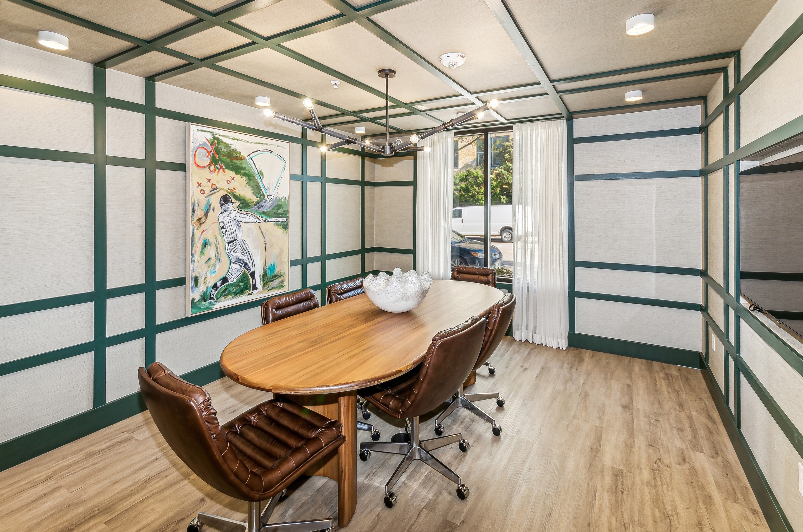 Conference room with a wooden table with leather chairs with green wood and beige paneling with a curtained window at AMLI at the Ballpark