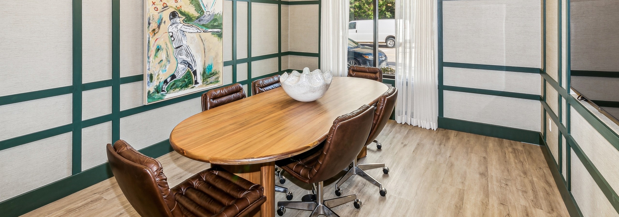 Conference room with a wooden table with leather chairs with green wood and beige paneling with a curtained window at AMLI at the Ballpark