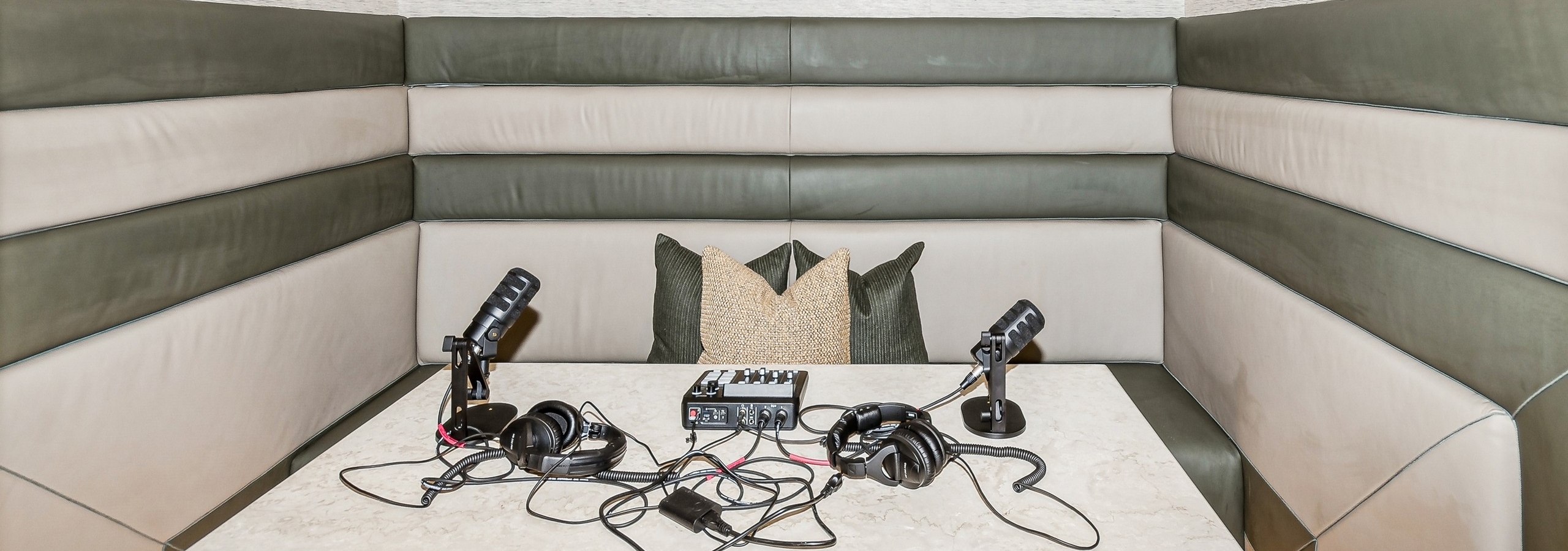 Podcast room with booth seating and olive and beige padded walls surrounding quartz table with recording equipment at AMLI at the Ballpark