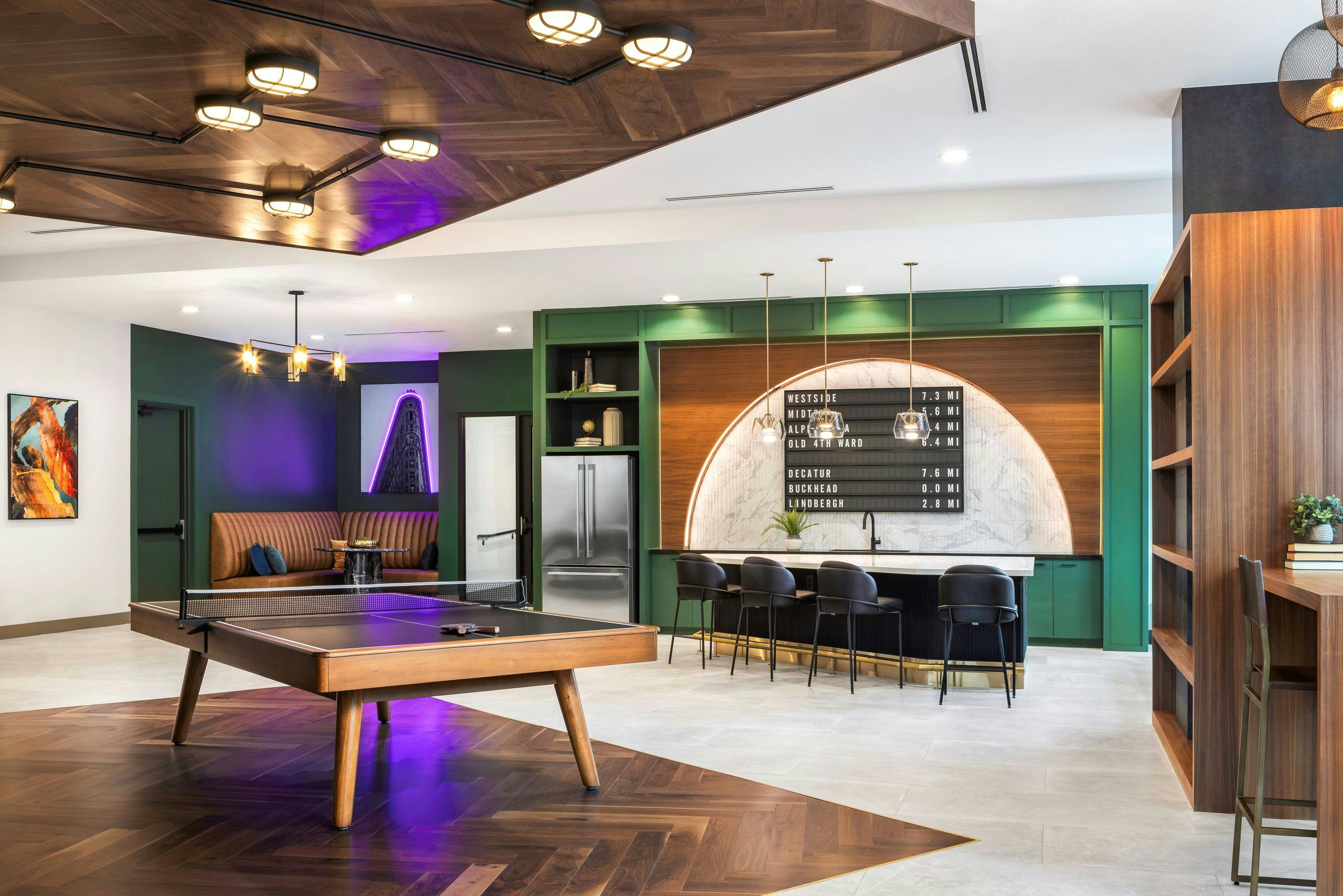 Modern resident lounge at AMLI Flatiron with wood and black ping pong table in front of island with 4 chairs and refrigerator and booth