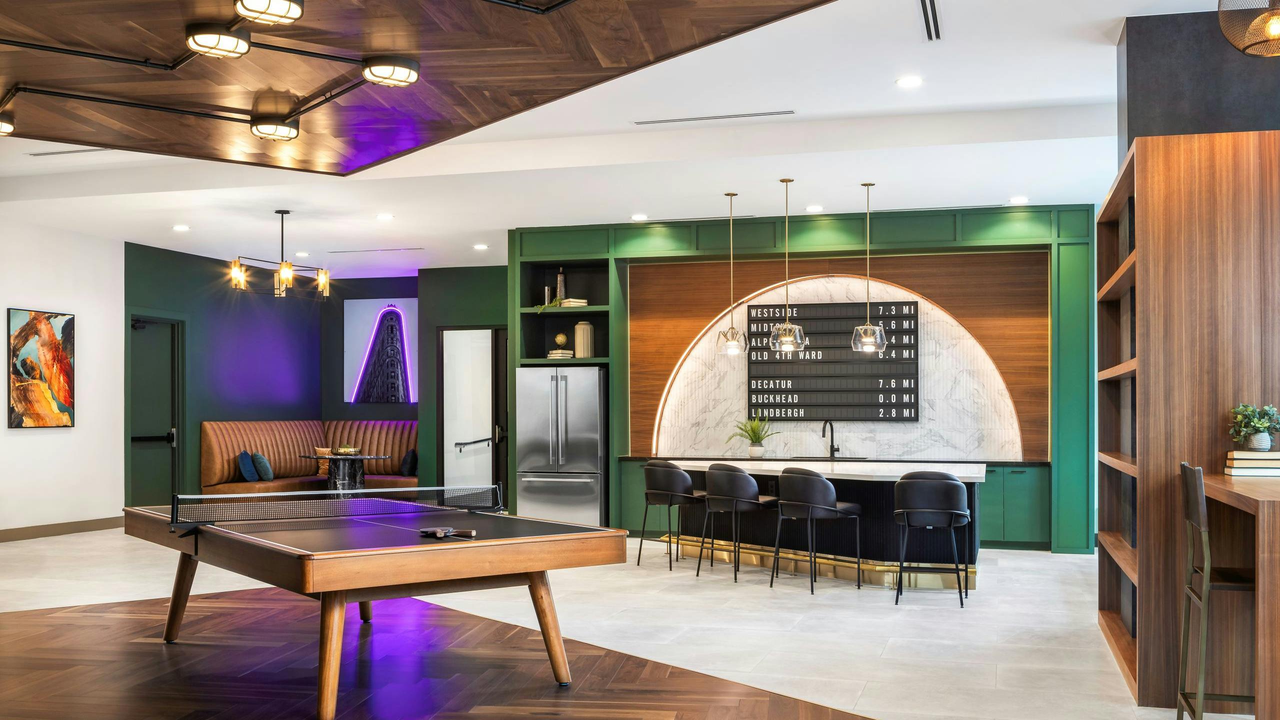 Modern resident lounge at AMLI Flatiron with wood and black ping pong table in front of island with 4 chairs and refrigerator and booth
