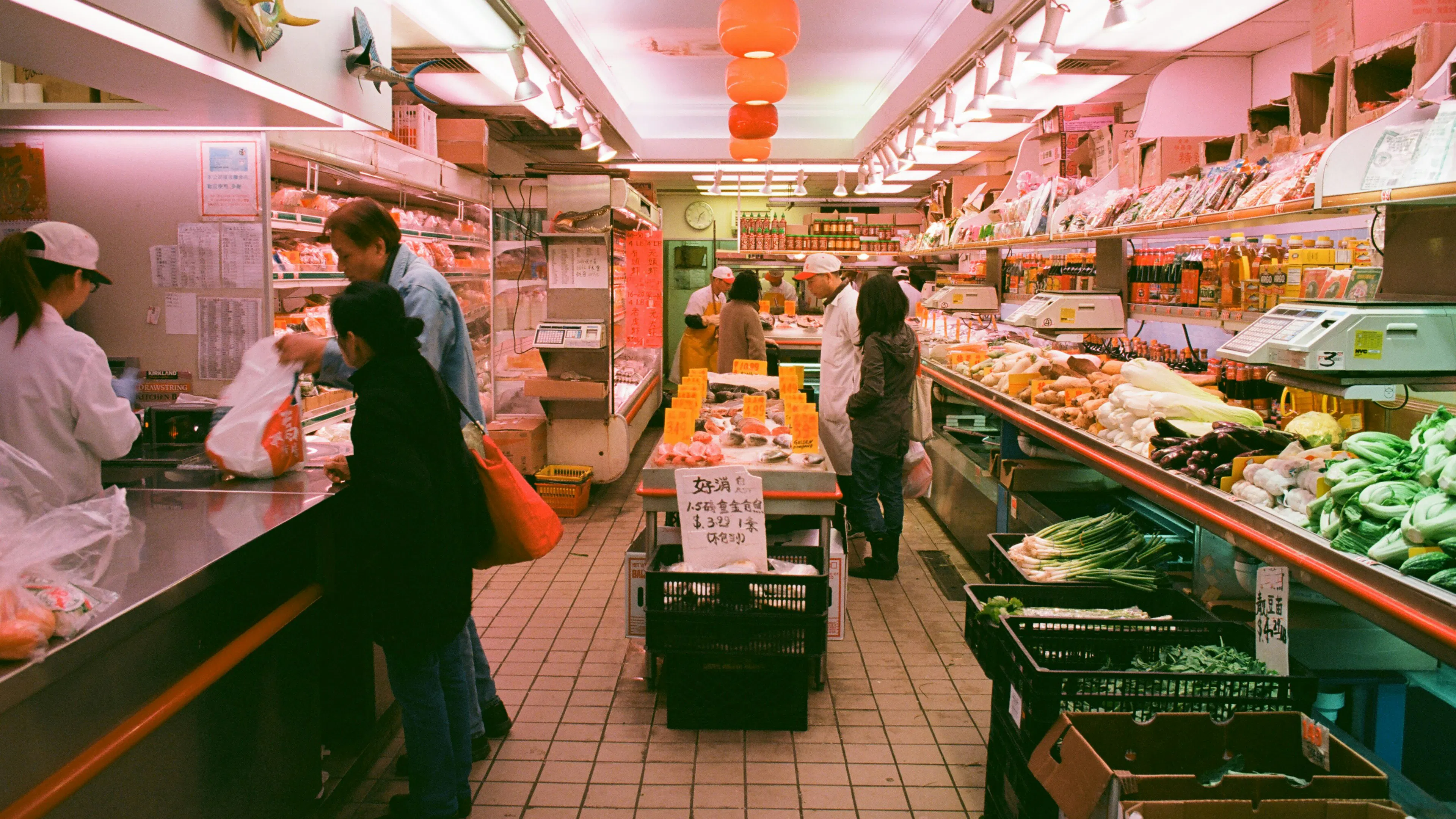 The interior of a butchery and grocery store with produce and cuts of meat displayed on the shelves above a tile floor