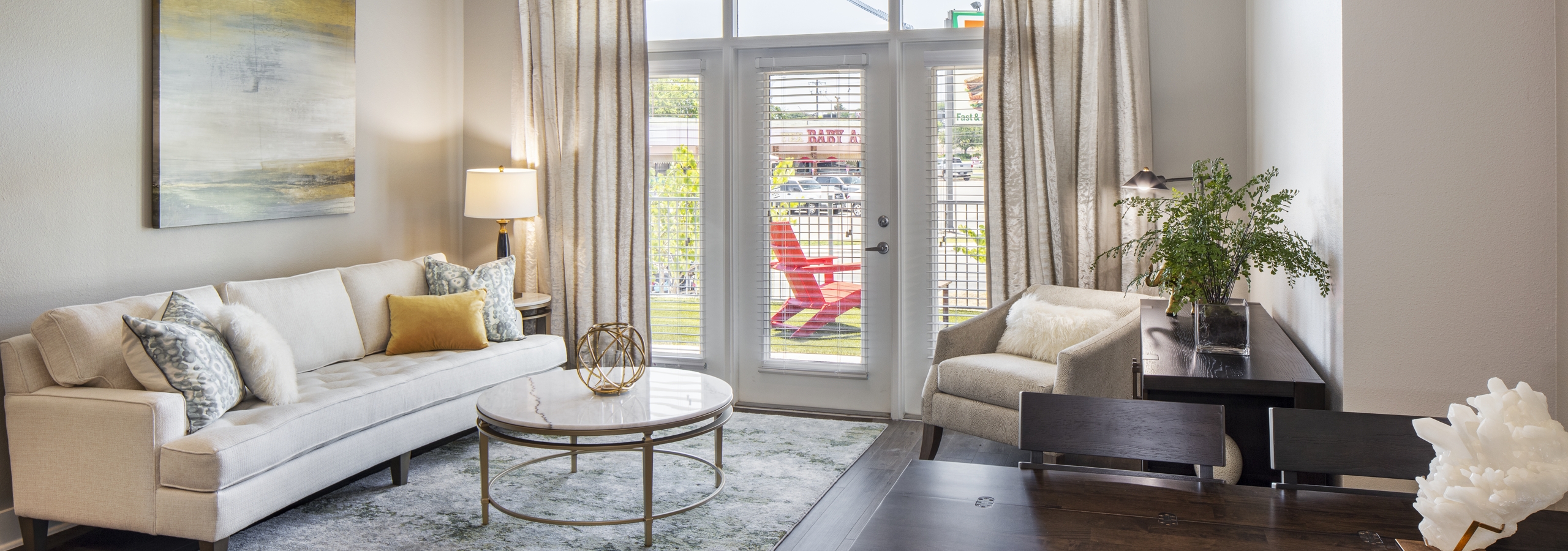 AMLI South Shore living room with dark hardwood and elegant decor with balcony doors revealing bright daytime view