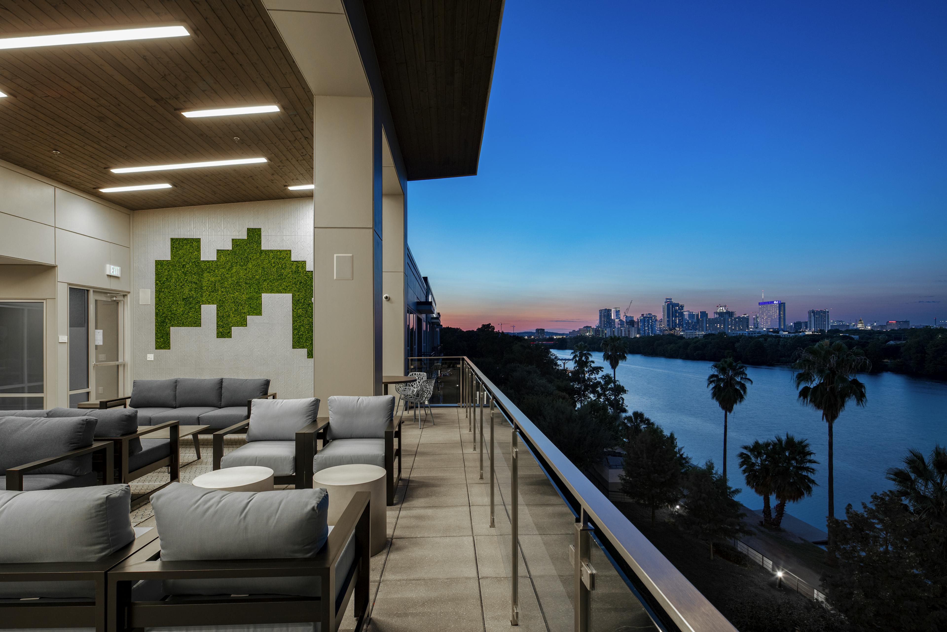 Rooftop deck at AMLI South Shore with cushion seating and scenic dusk views of Lady Bird Lake and downtown Austin skyline