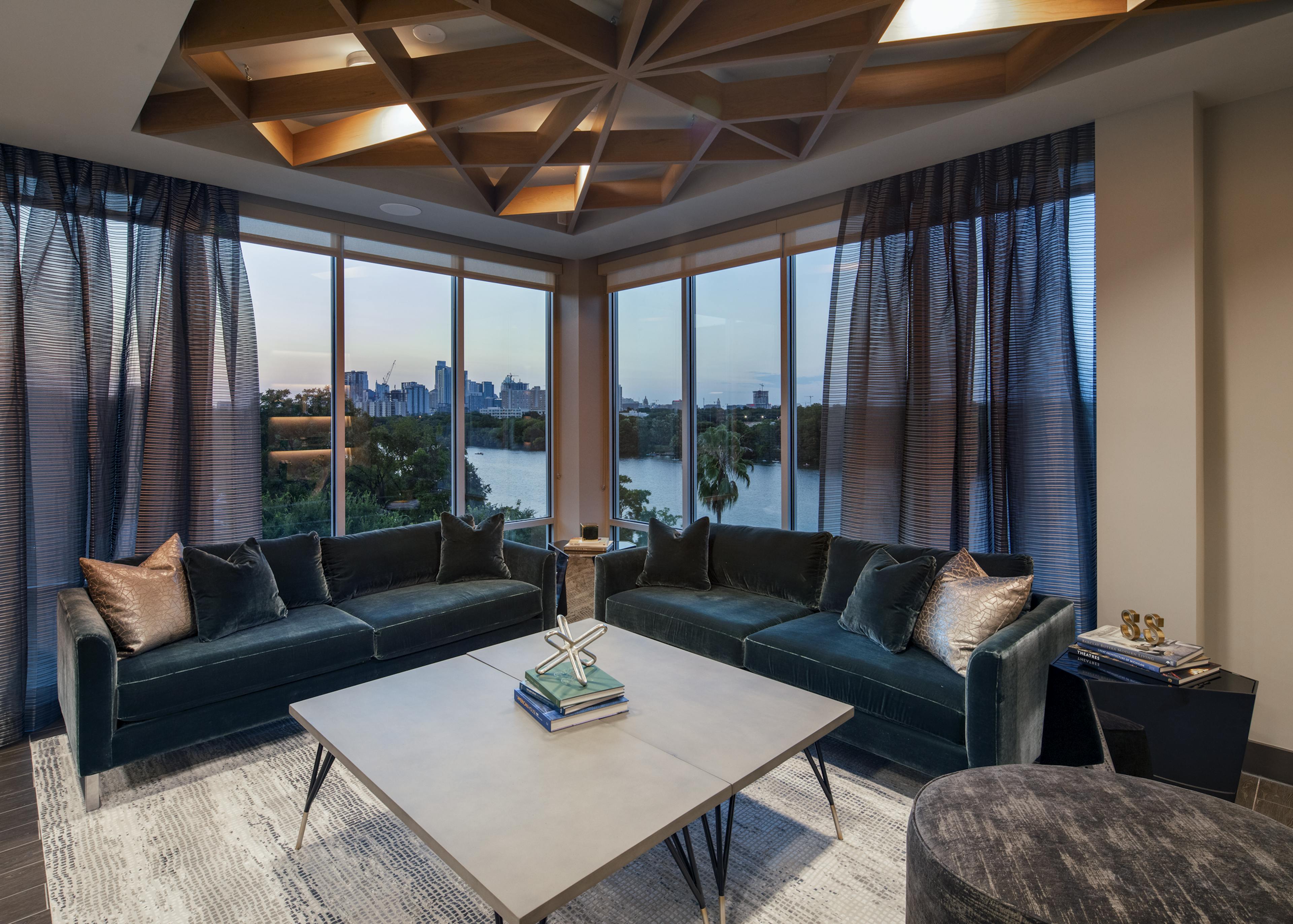 Resident lounge at AMLI South Shore with blue velvet couches large curtained windows showcasing the lake at dusk