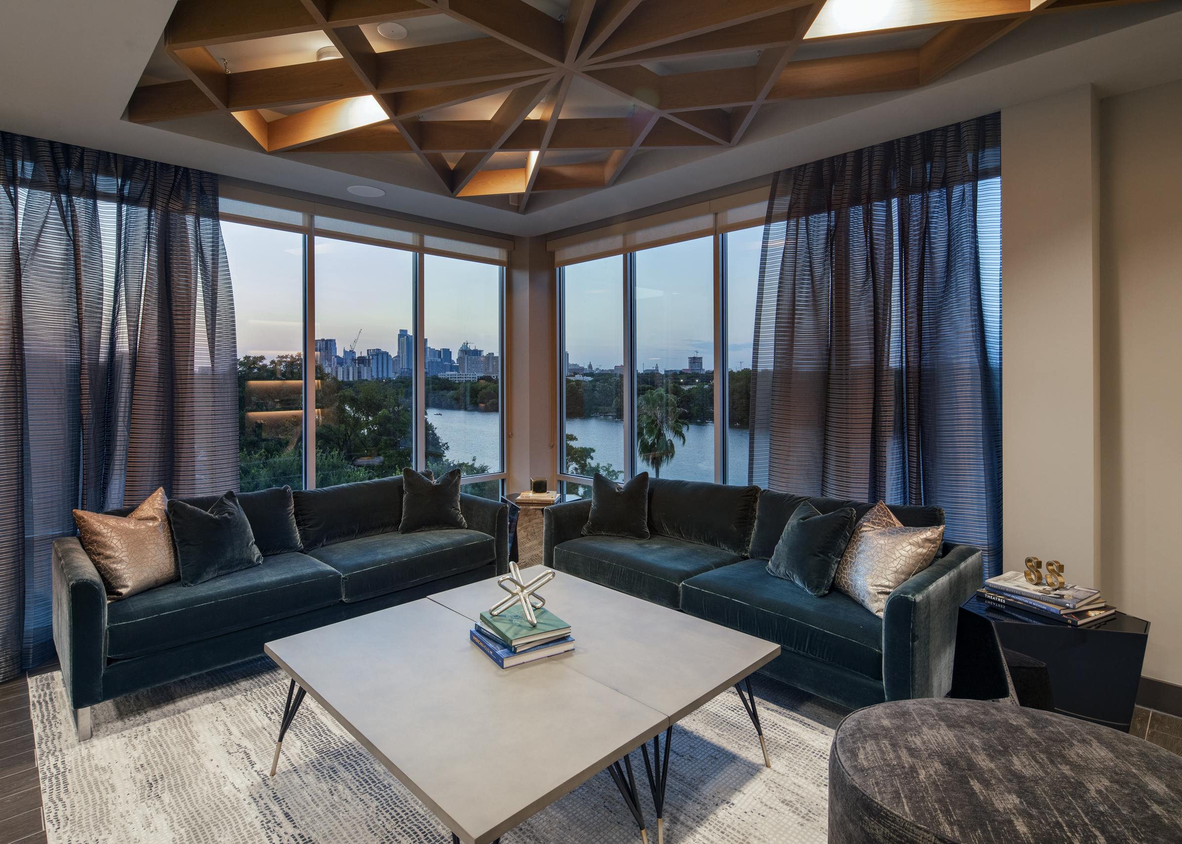 Resident lounge at AMLI South Shore with blue velvet couches large curtained windows showcasing the lake at dusk