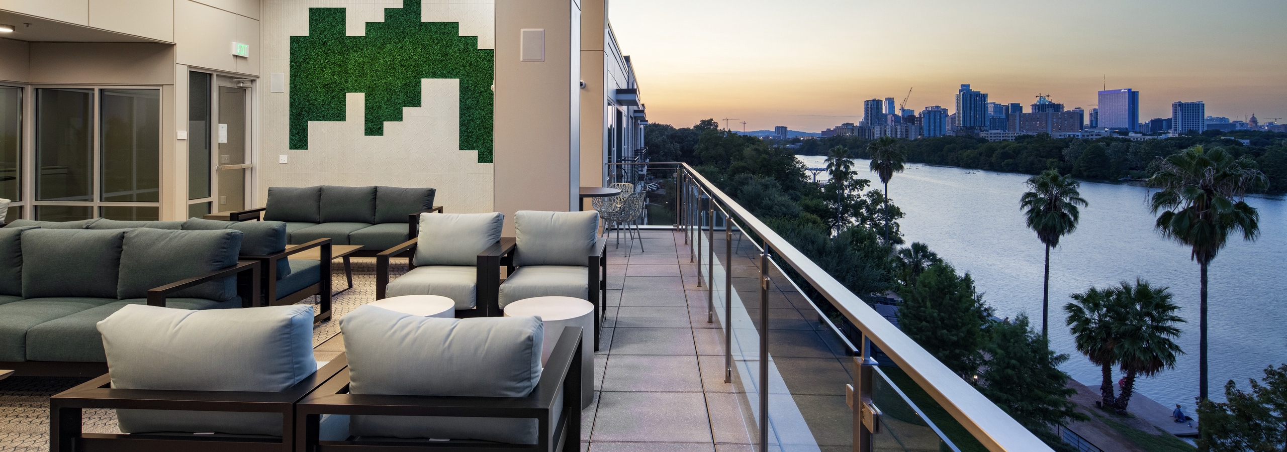 Resident lounge at AMLI South Shore with blue velvet couches large curtained windows showcasing the lake at dusk