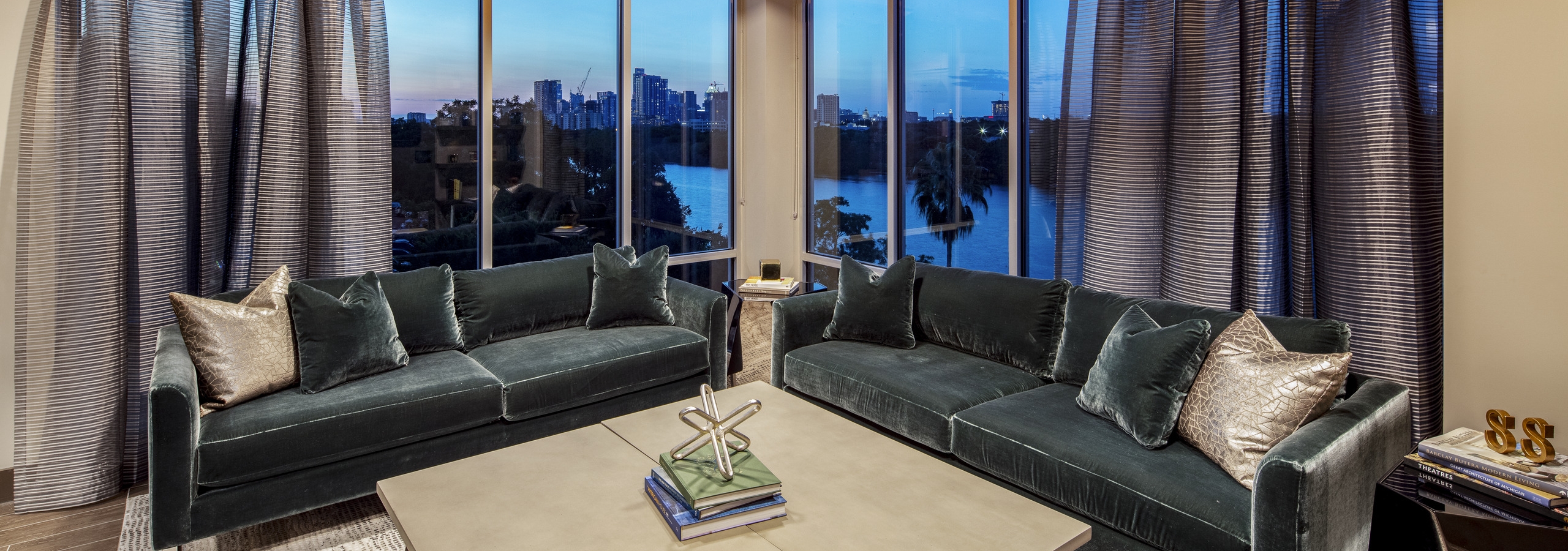 Resident lounge at AMLI South Shore with blue velvet couches large curtained windows showcasing the lake at dusk
