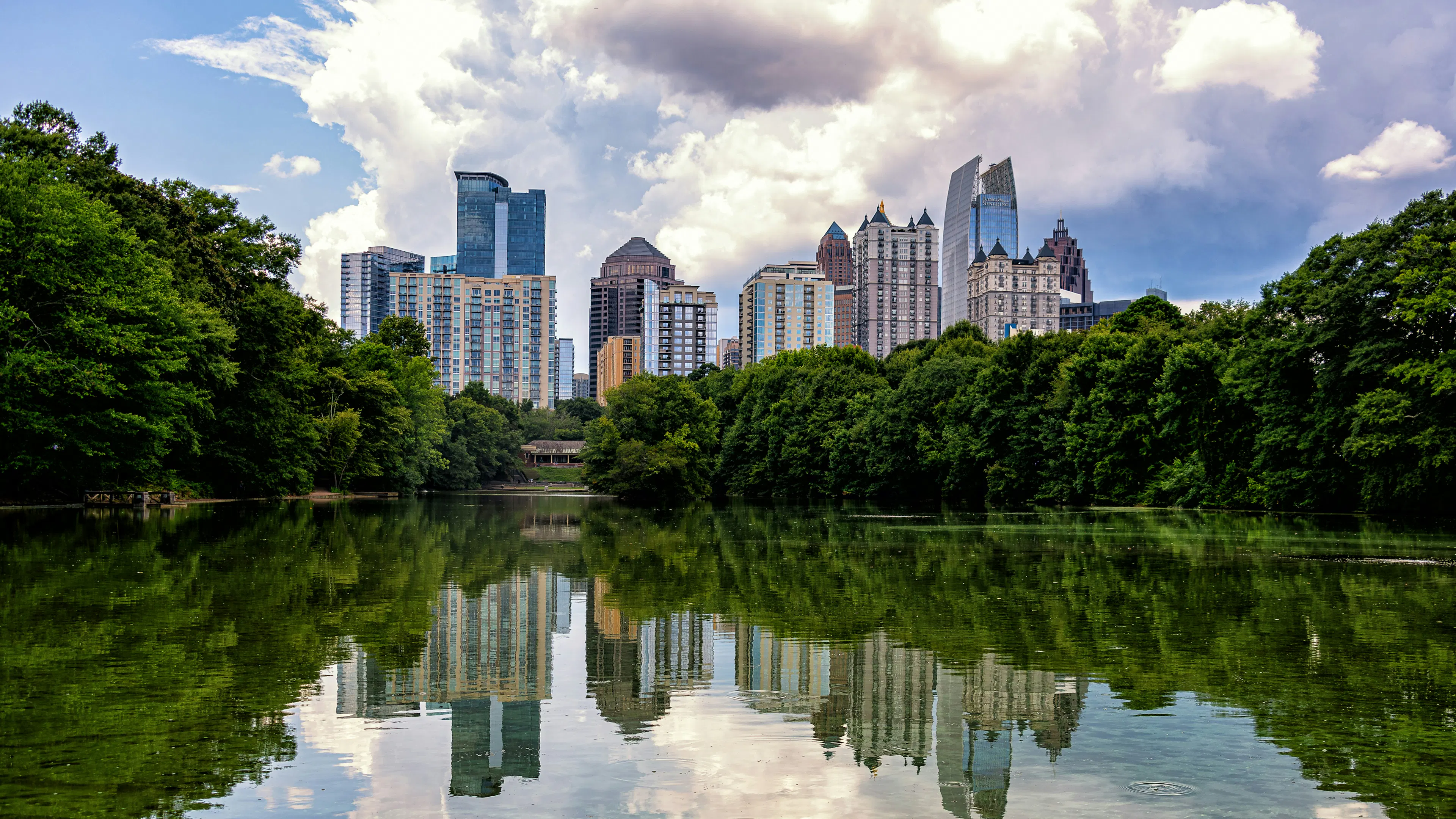 Atlanta's downtown skyline with green trees and a lake in the foreground
