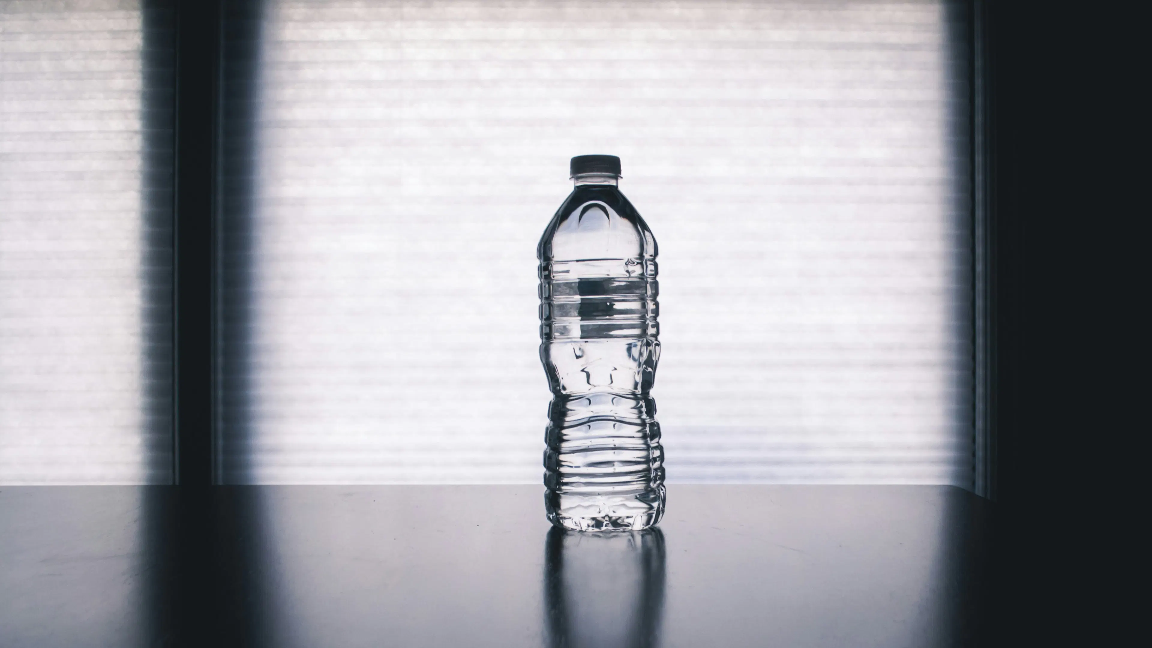 A label-free bottle of water against a grey background