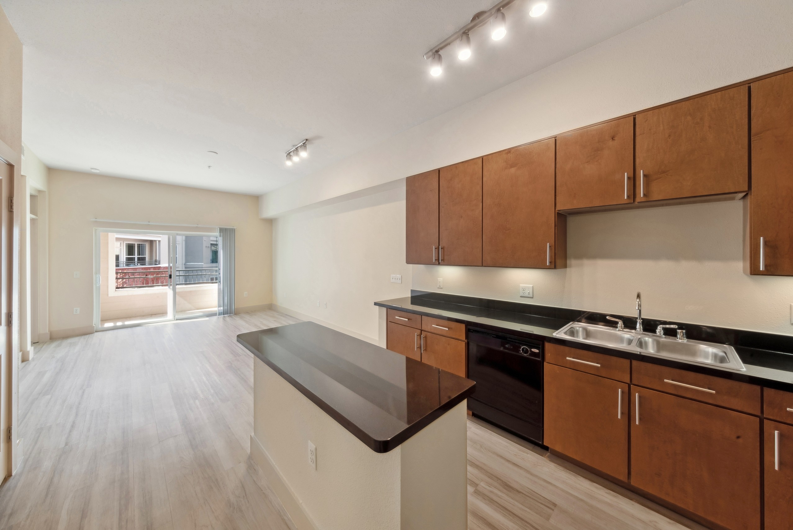 AMLI Park Avenue kitchen with wood cabinets and black appliances with a central island overlooking the living room and balcony