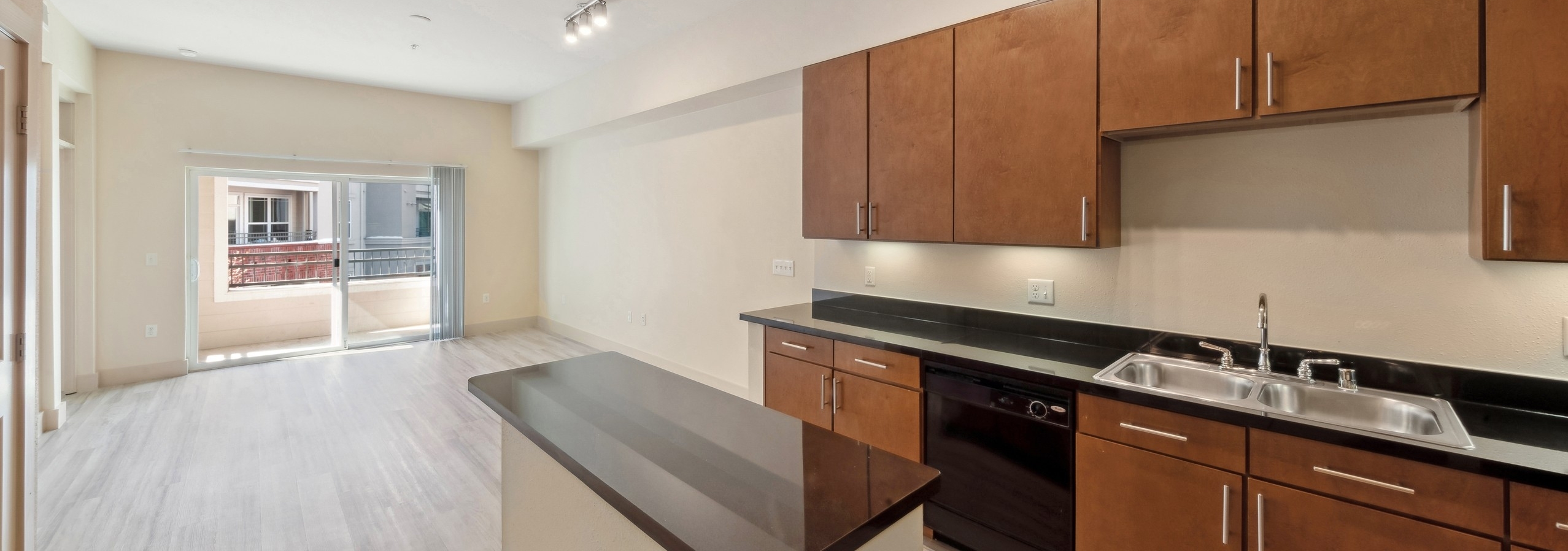 AMLI Park Avenue kitchen with wood cabinets and black appliances with a central island overlooking the living room and balcony
