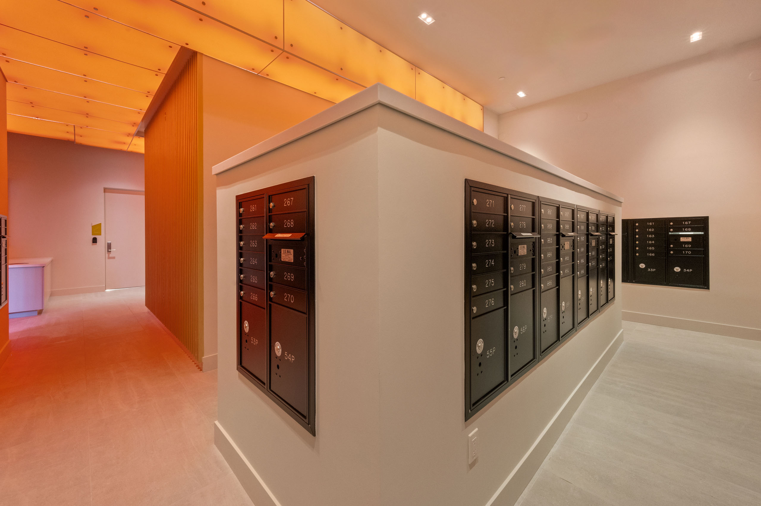 AMLI Wynwood black metal mailboxes  built into an interior wall illuminated by warm orange overhead lights