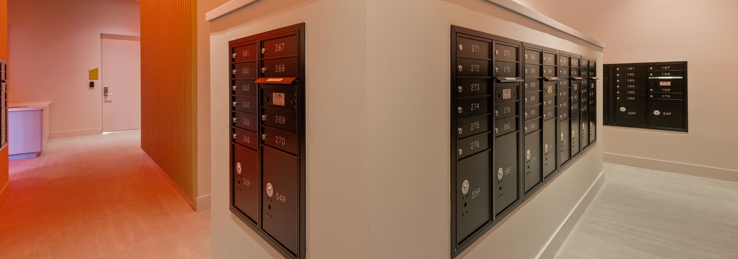 AMLI Wynwood black metal mailboxes  built into an interior wall illuminated by warm orange overhead lights