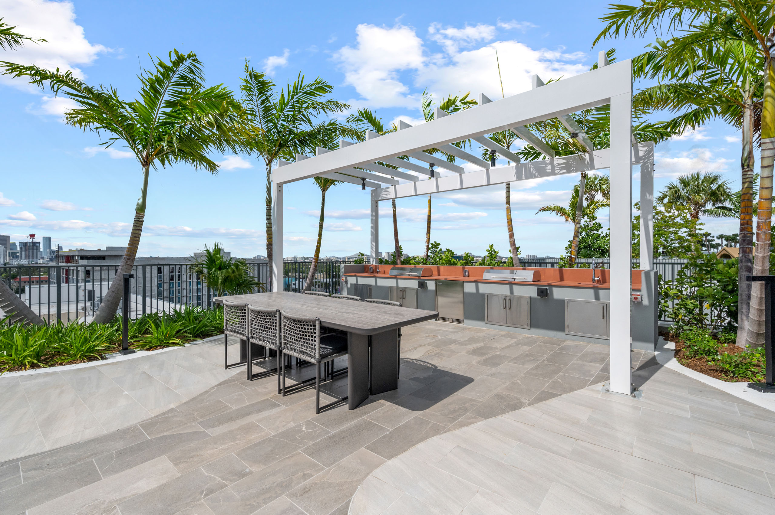 A daytime view of a covered area at AMLI Wynwood apartments with two large grills built into an outdoor kitchen counter and a dining table