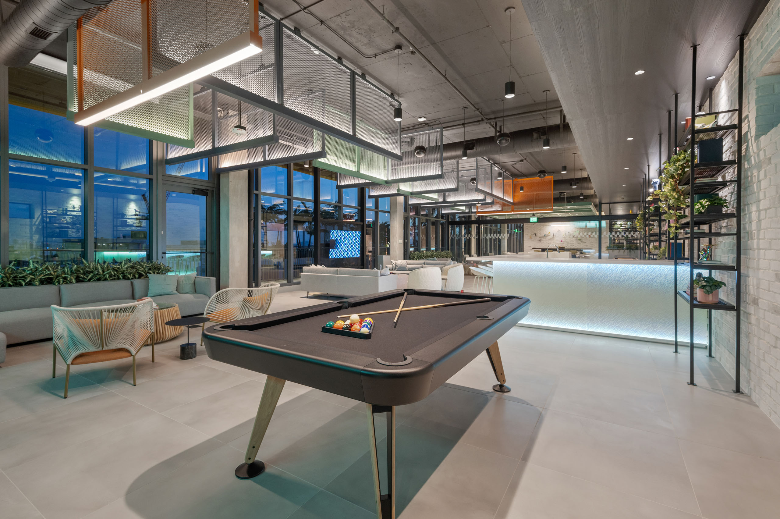 AMLI Wynwood sky lounge with industrial lighting over a billiards table and illuminated bar and designer tables and chairs