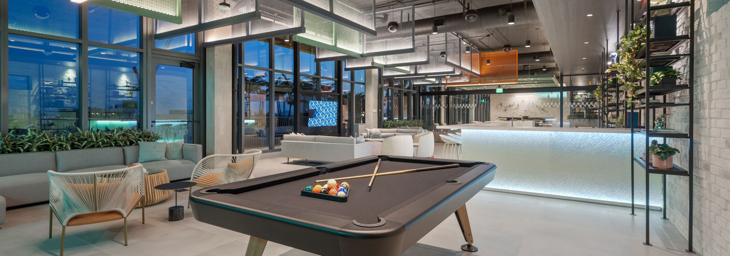 AMLI Wynwood sky lounge with industrial lighting over a billiards table and illuminated bar and designer tables and chairs